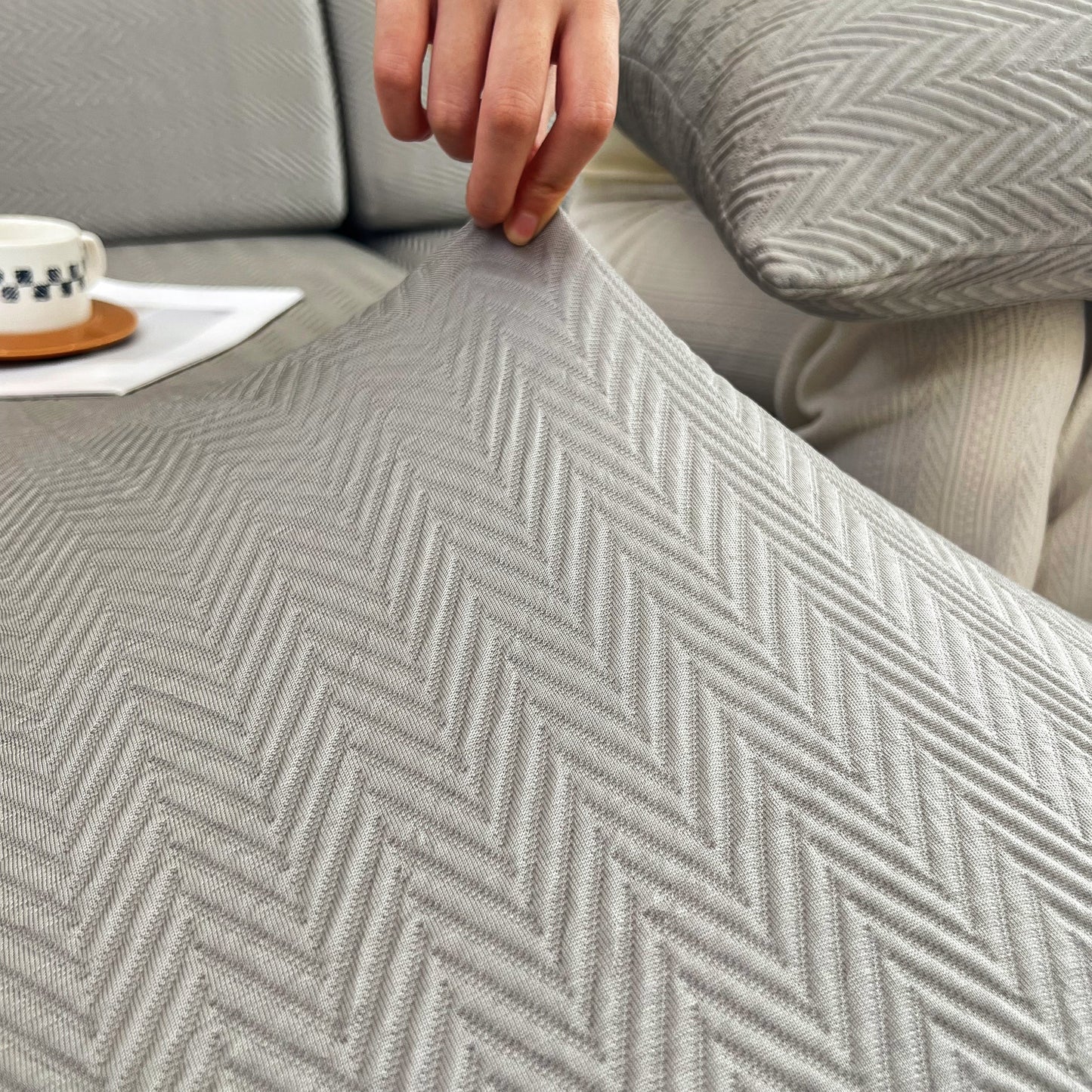 Person stretching Cooling Stretchy Replacement Couch Cushion Covers for Sectional, Individual Couch Seat Cushion Covers in grey fabric.