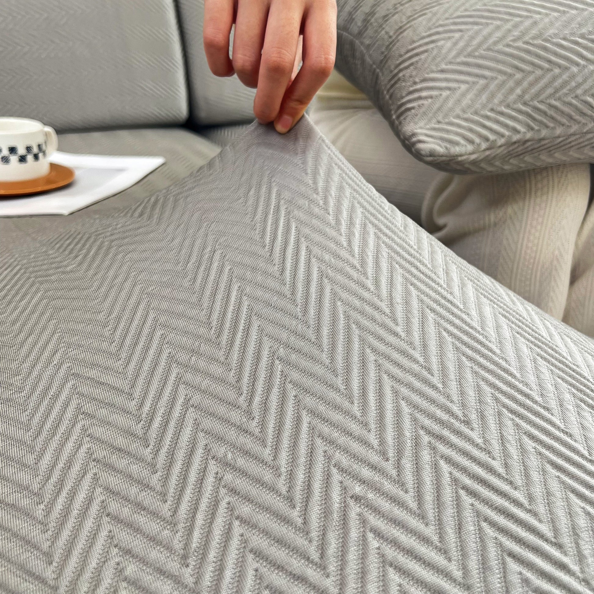 Person stretching Cooling Stretchy Replacement Couch Cushion Covers for Sectional, Individual Couch Seat Cushion Covers in grey fabric.
