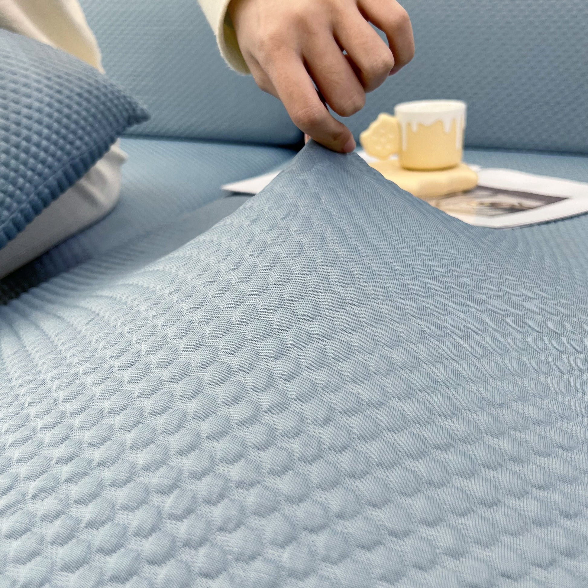 Person adjusting Cooling Stretch Sofa Seat Cushion Covers on a couch, demonstrating the universal fit and slip cover design.
