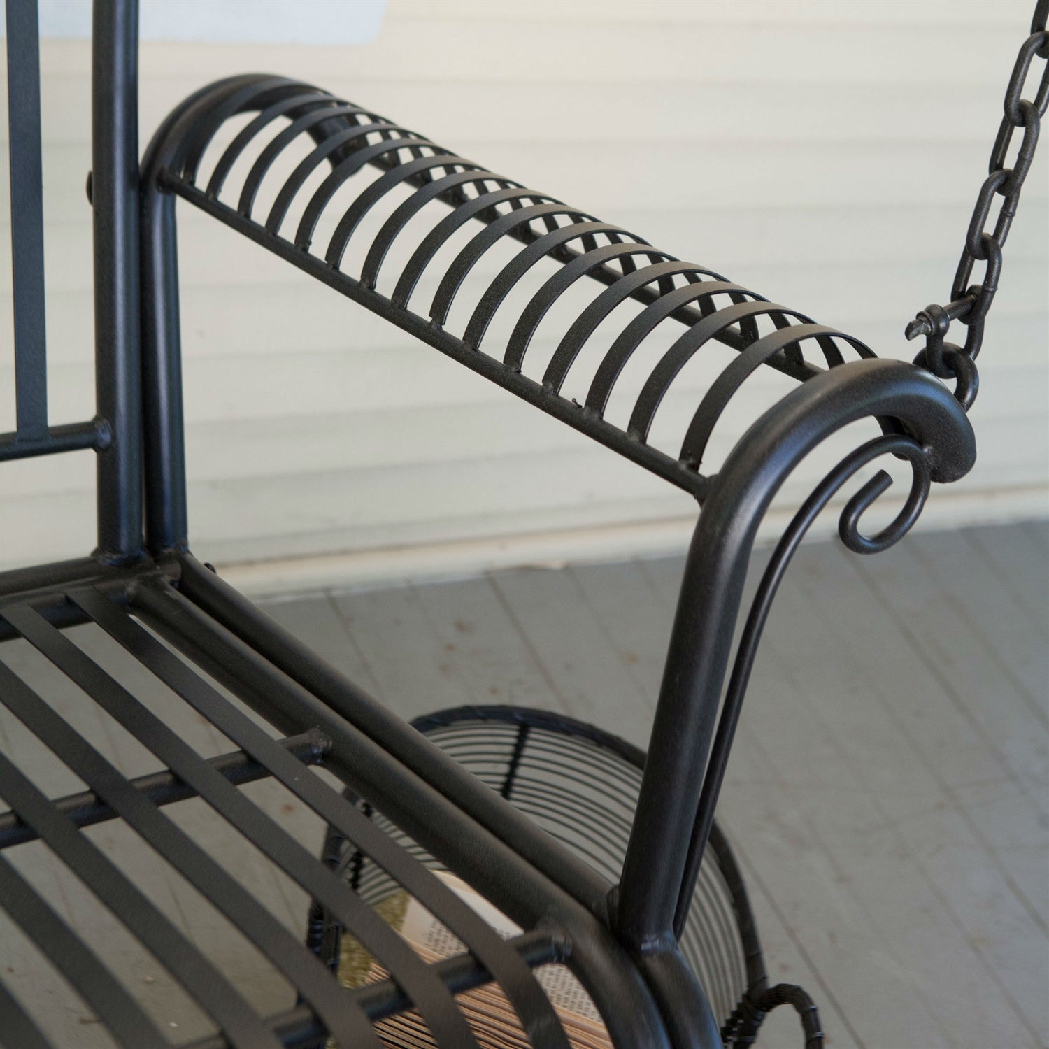 Wrought Iron Outdoor Patio 4-Ft Porch Swing in Black with scrolled arm design and slatted backrest for comfort and style.