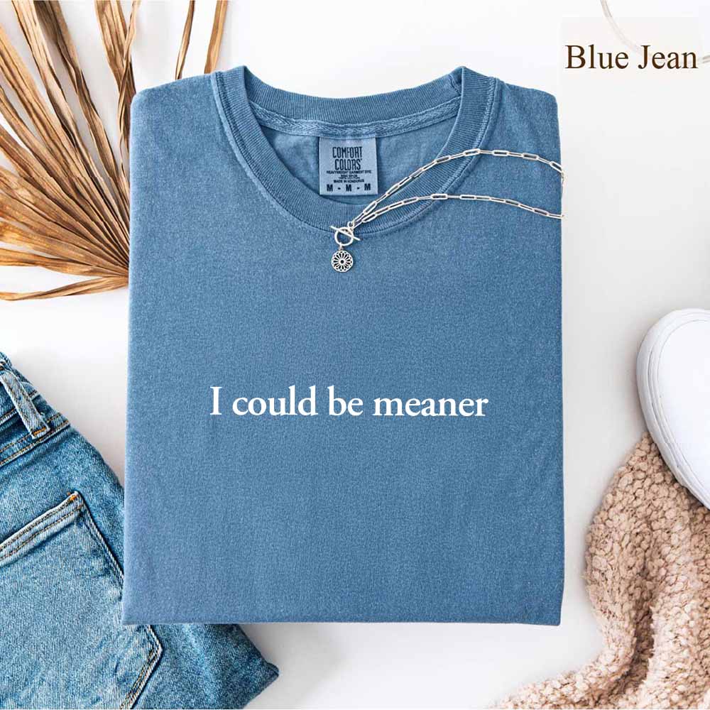 I Could Be Meaner Funny Sarcastic Tee in blue, folded with accessories, trendy streetwear for sassy everyday style.