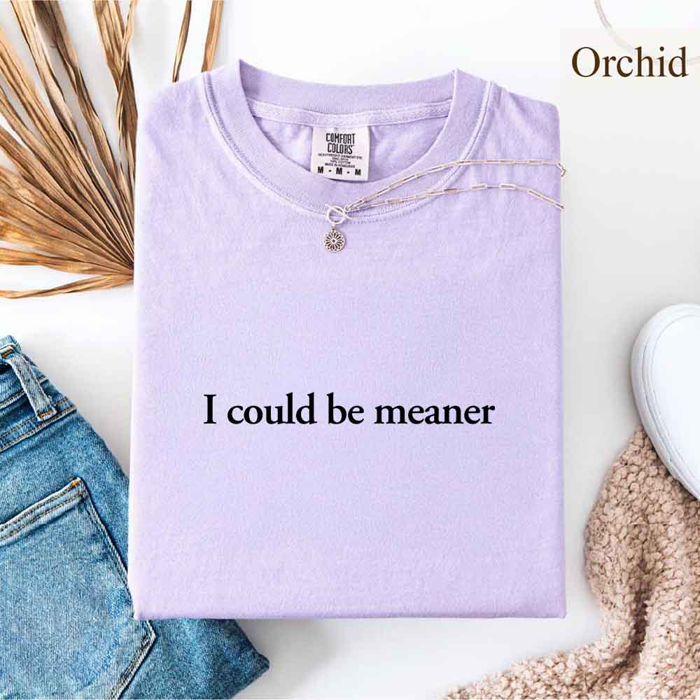I Could Be Meaner Funny Sarcastic Tee folded on a table with necklace and denim, trendy streetwear fashion.