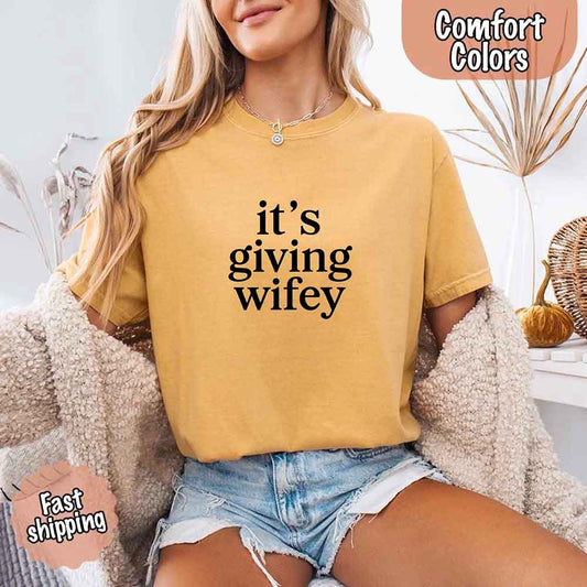 Woman wearing Its Giving Wifey Comfort Colors Tee, perfect bridal or wedding gift shirt with fast shipping.