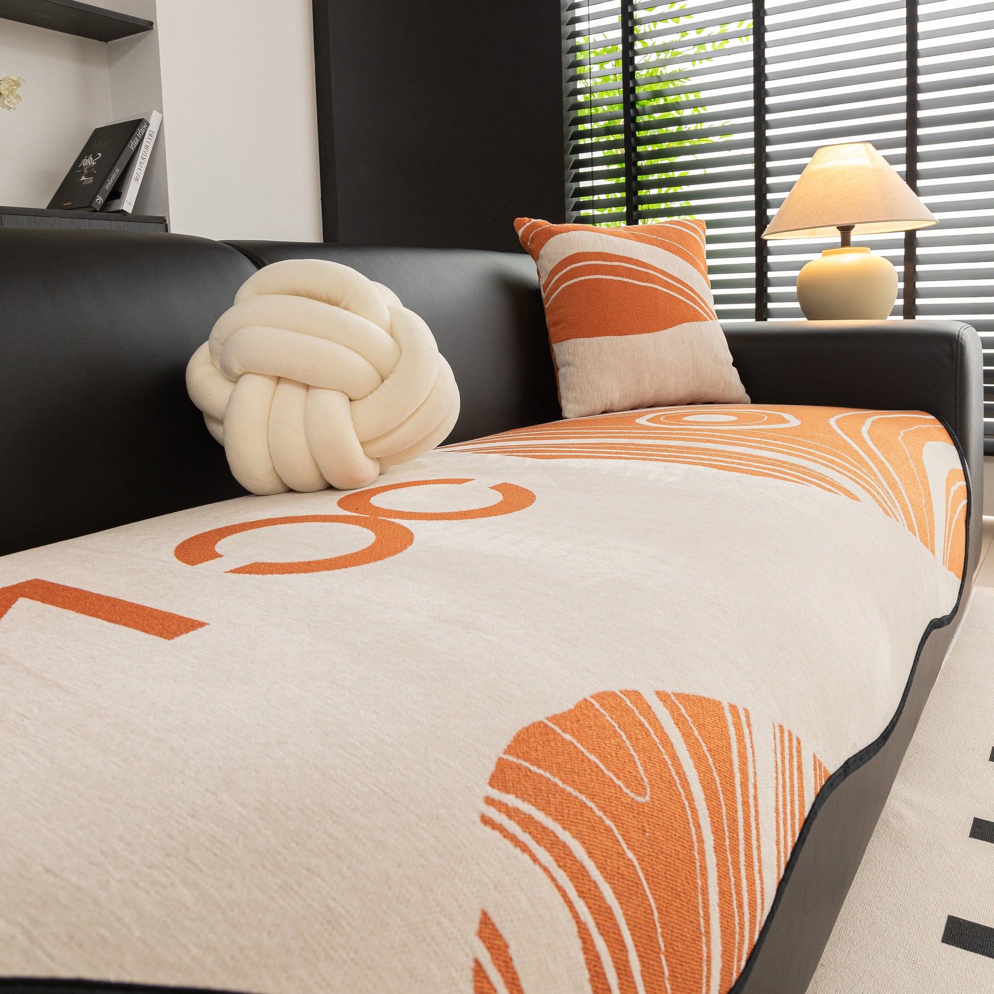 Abstract Art Sofa Cover with Wave Edge, Non Slip Couch Cover for Stylish Homes on modern black couch with orange abstract design.
