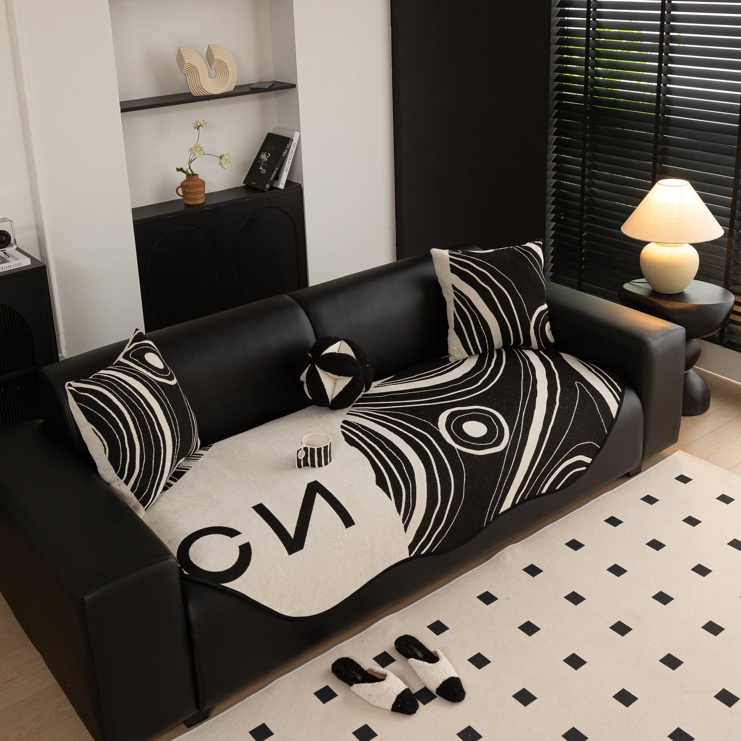 Abstract Art Sofa Cover with Wave Edge, Non Slip Couch Cover for Stylish Homes displayed on a black sofa in a modern living room.