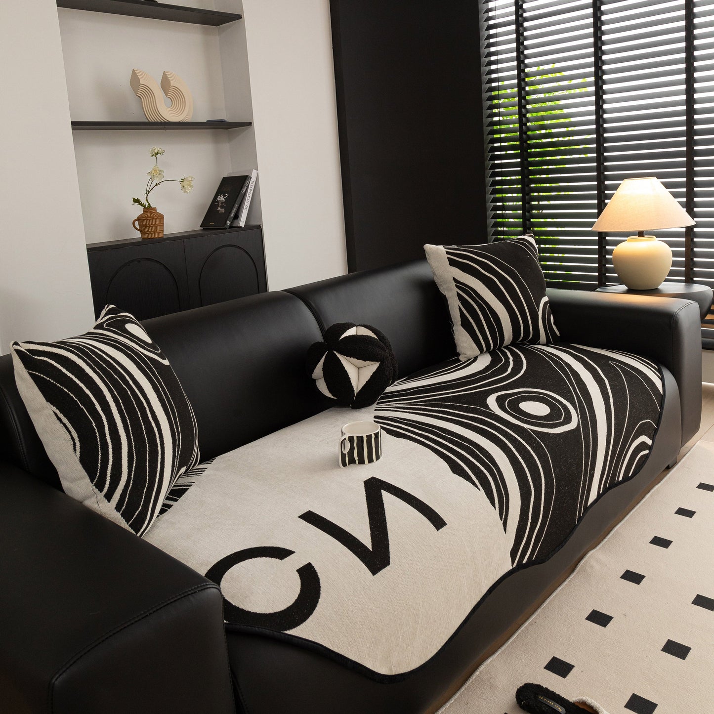 Abstract Art Sofa Cover with Wave Edge, Non Slip Couch Cover for Stylish Homes in black and cream with bold patterns on a black couch.