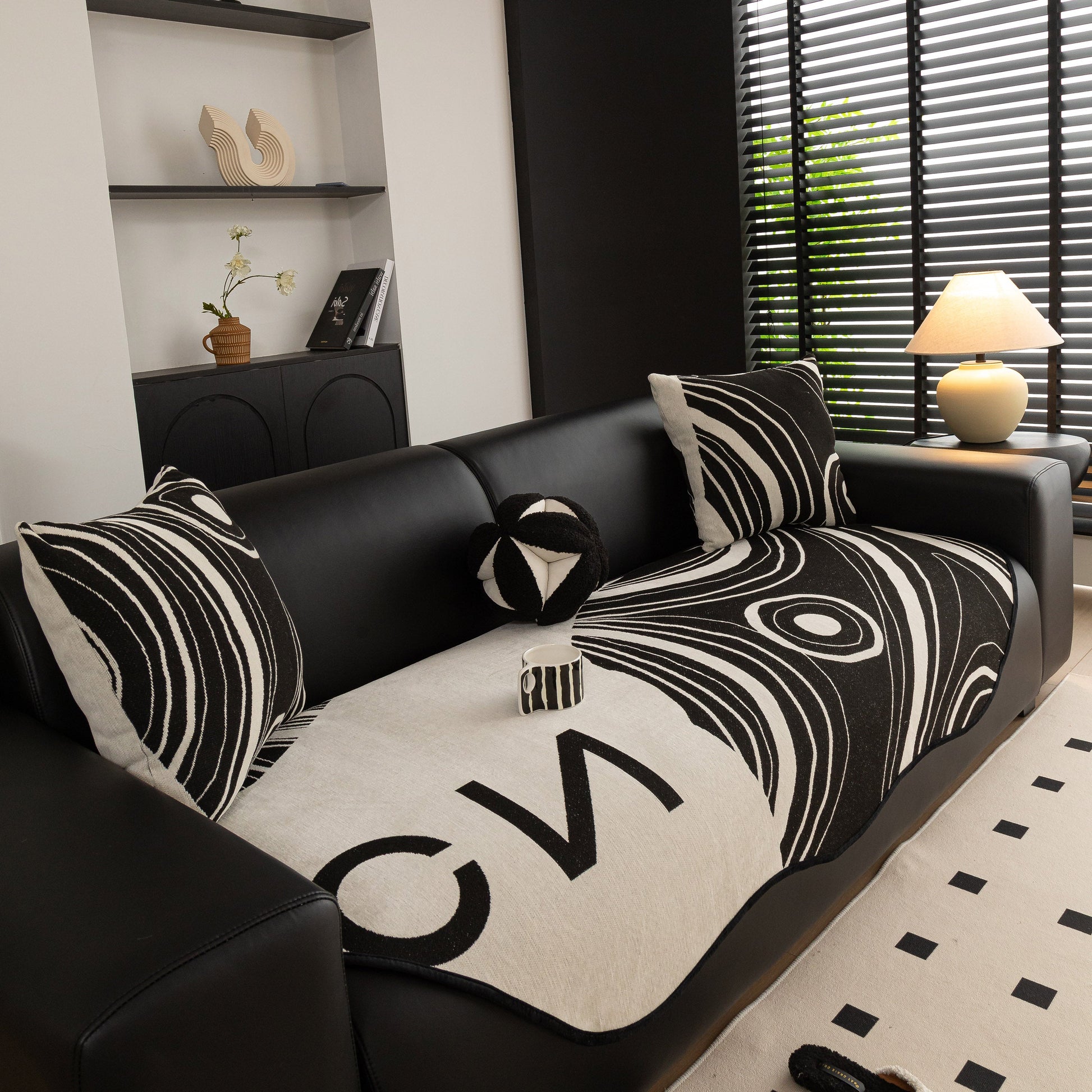 Abstract Art Sofa Cover with Wave Edge, Non Slip Couch Cover for Stylish Homes in black and cream with bold patterns on a black couch.