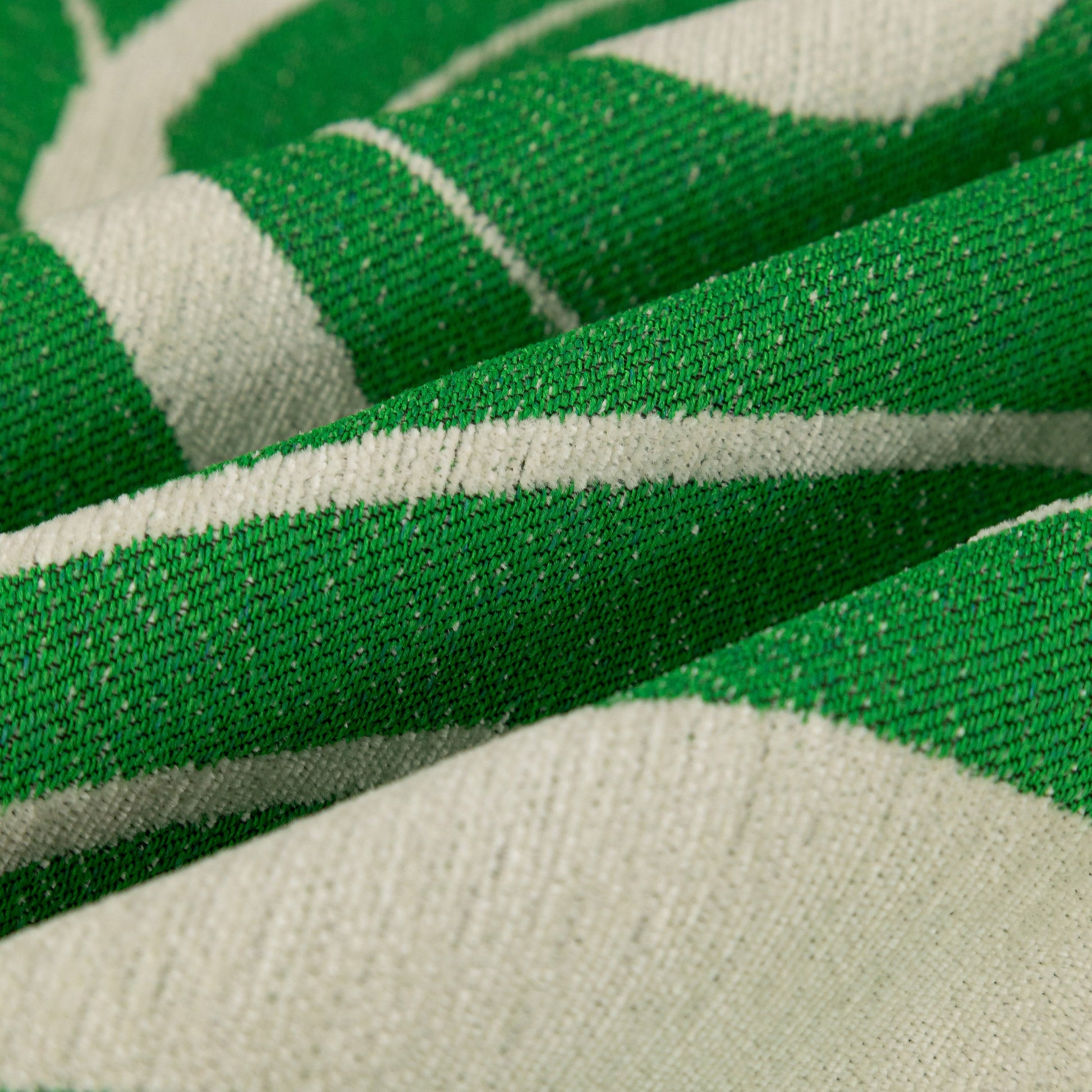 Close-up of green abstract art sofa cover with wave edge, non slip couch cover for stylish homes with chenille fabric texture.