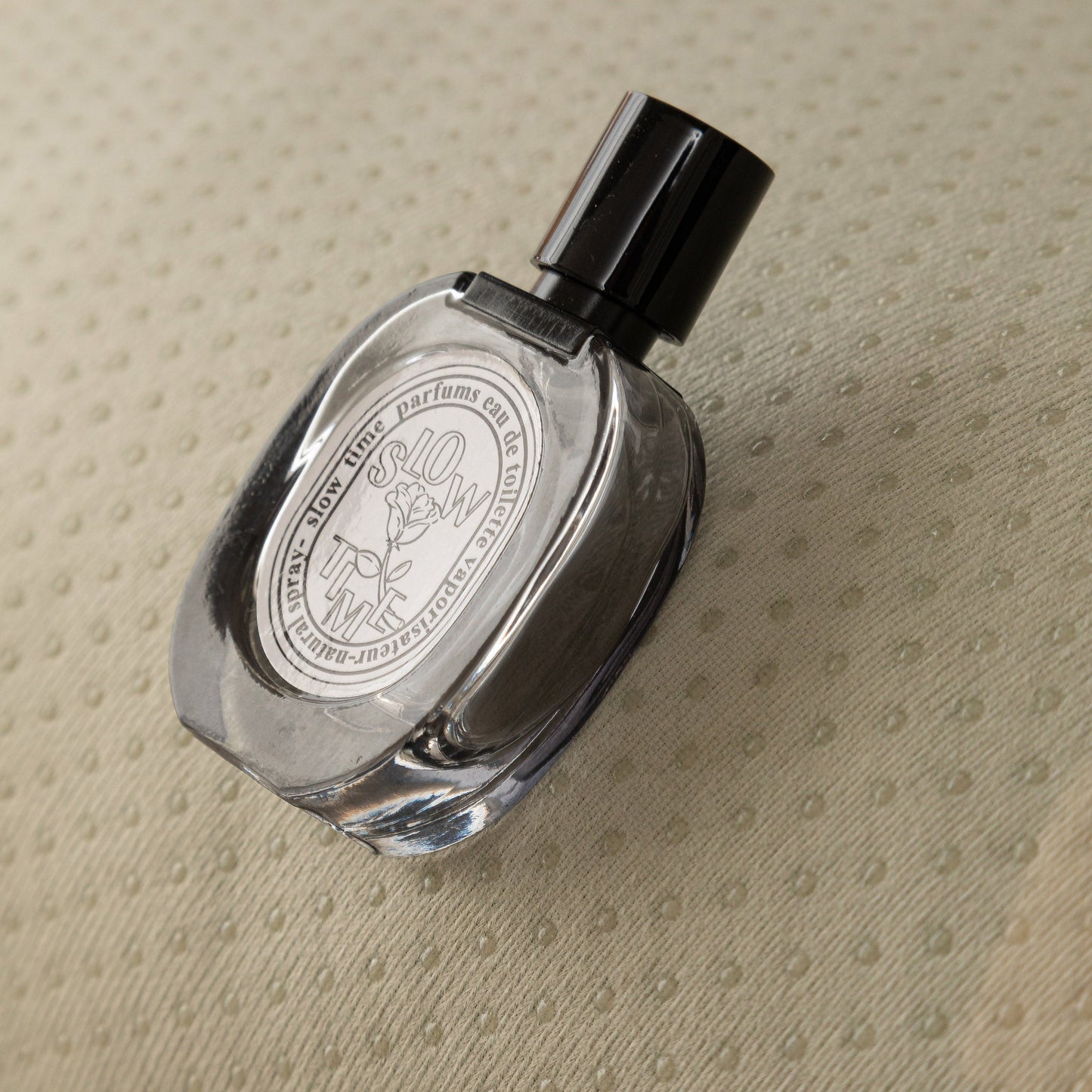 Glass perfume bottle on textured fabric background