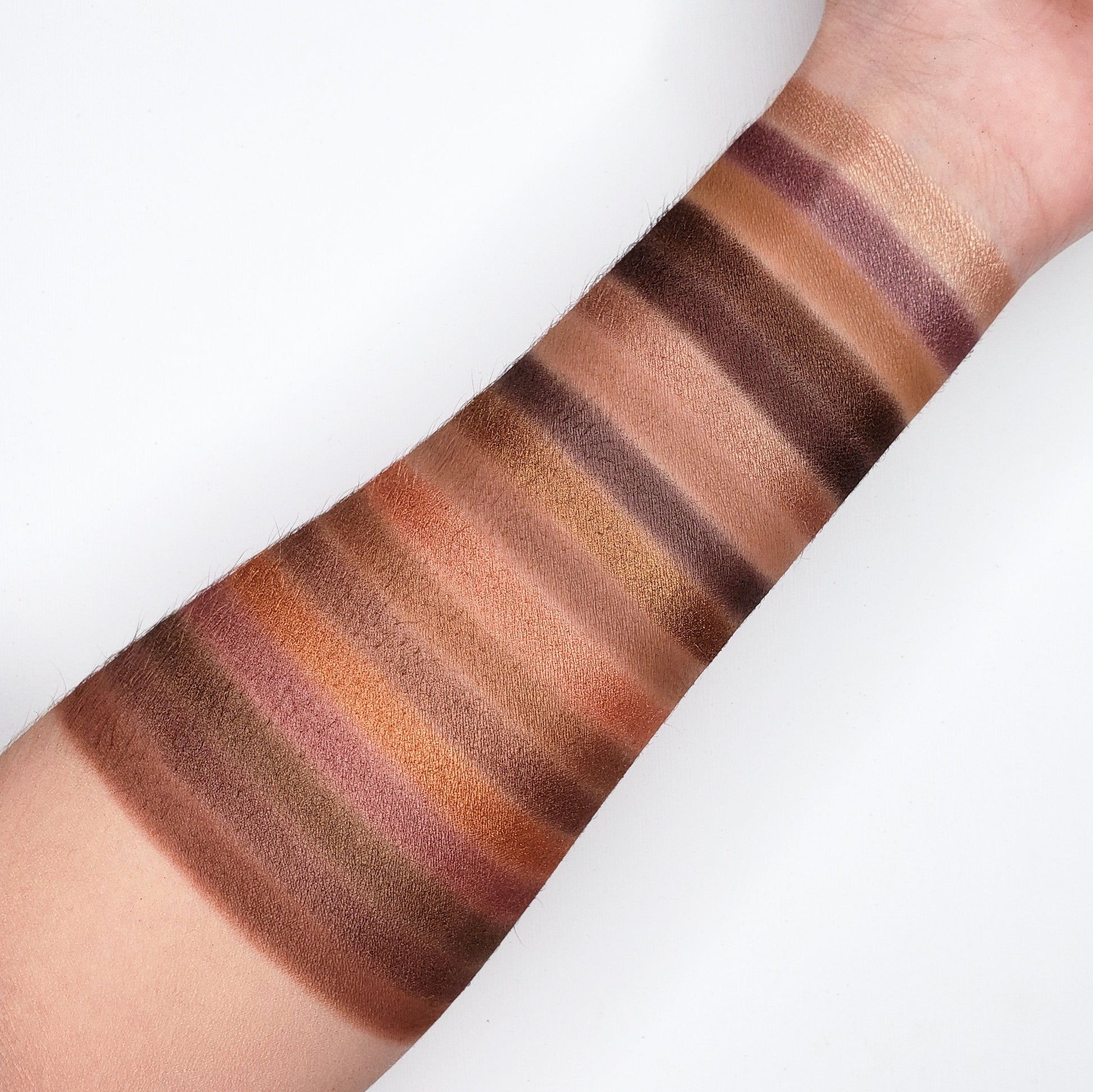 Swatches of JAVA EYESHADOW PALETTE 35J featuring warm browns, golds, and mauve tones on forearm.