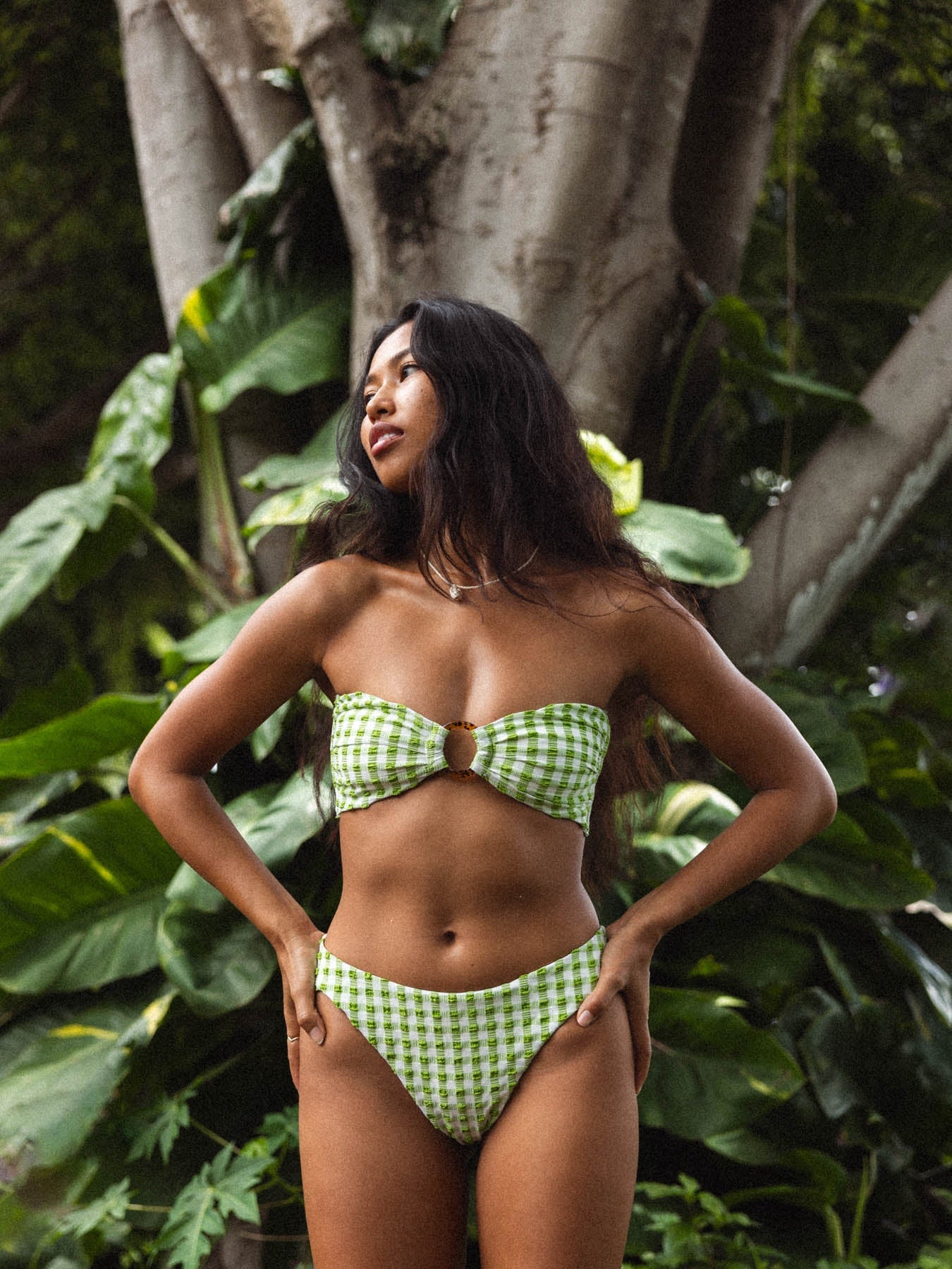 Model wearing kenna top - copenhagen green gingham strapless bandeau with gold ring and tie back in a natural setting.