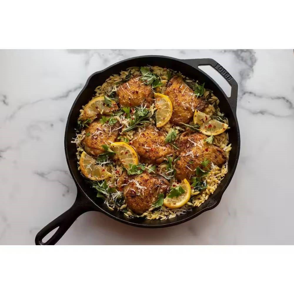 12-inch Cast Iron Skillet Frying Pan with Pour Spout - Made in the USA, filled with seasoned chicken and lemon slices on a marble countertop