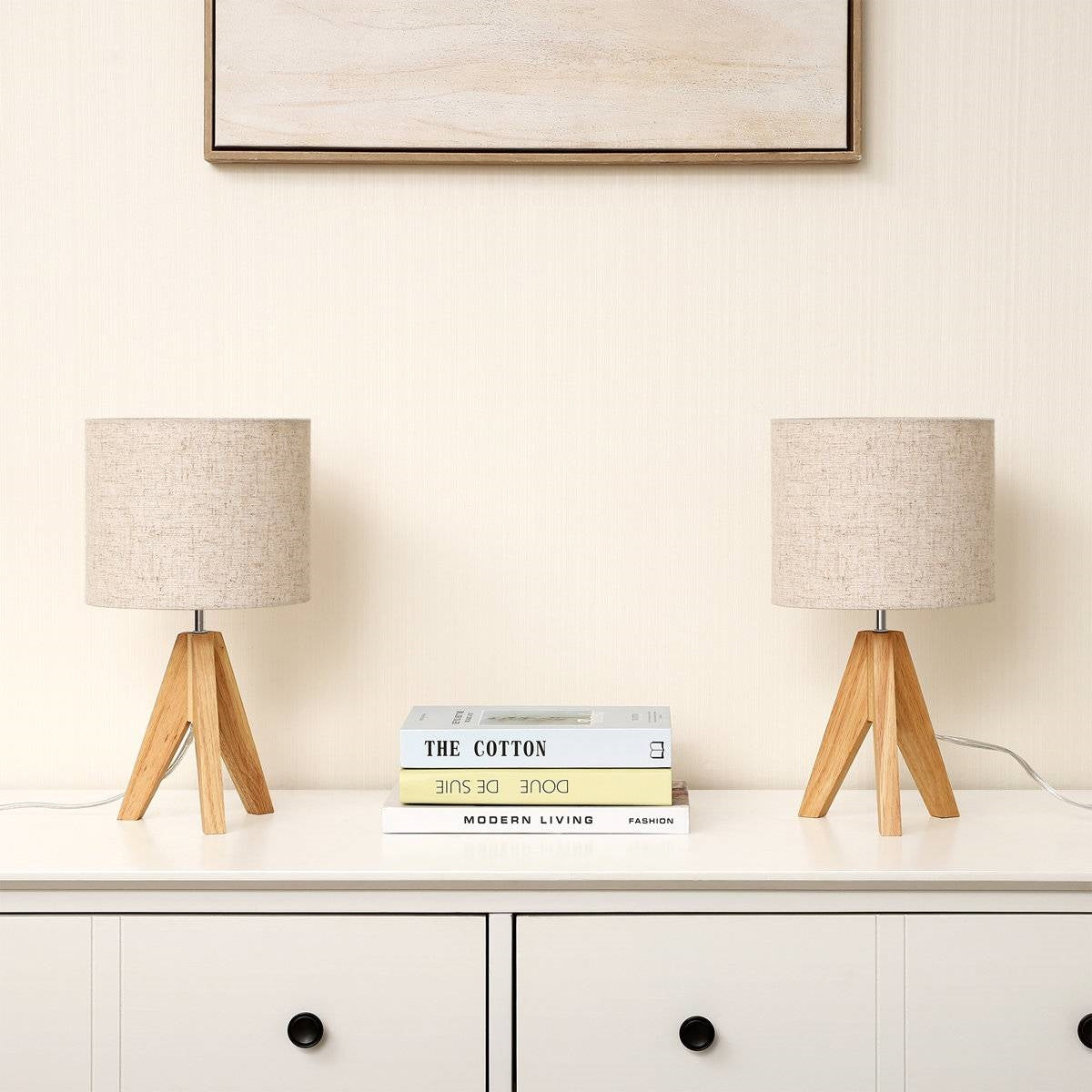 Set of 2 - Solid Wood Tripod Table Lamp with Beige Linen Drum Shade on a white cabinet next to books in a modern living room