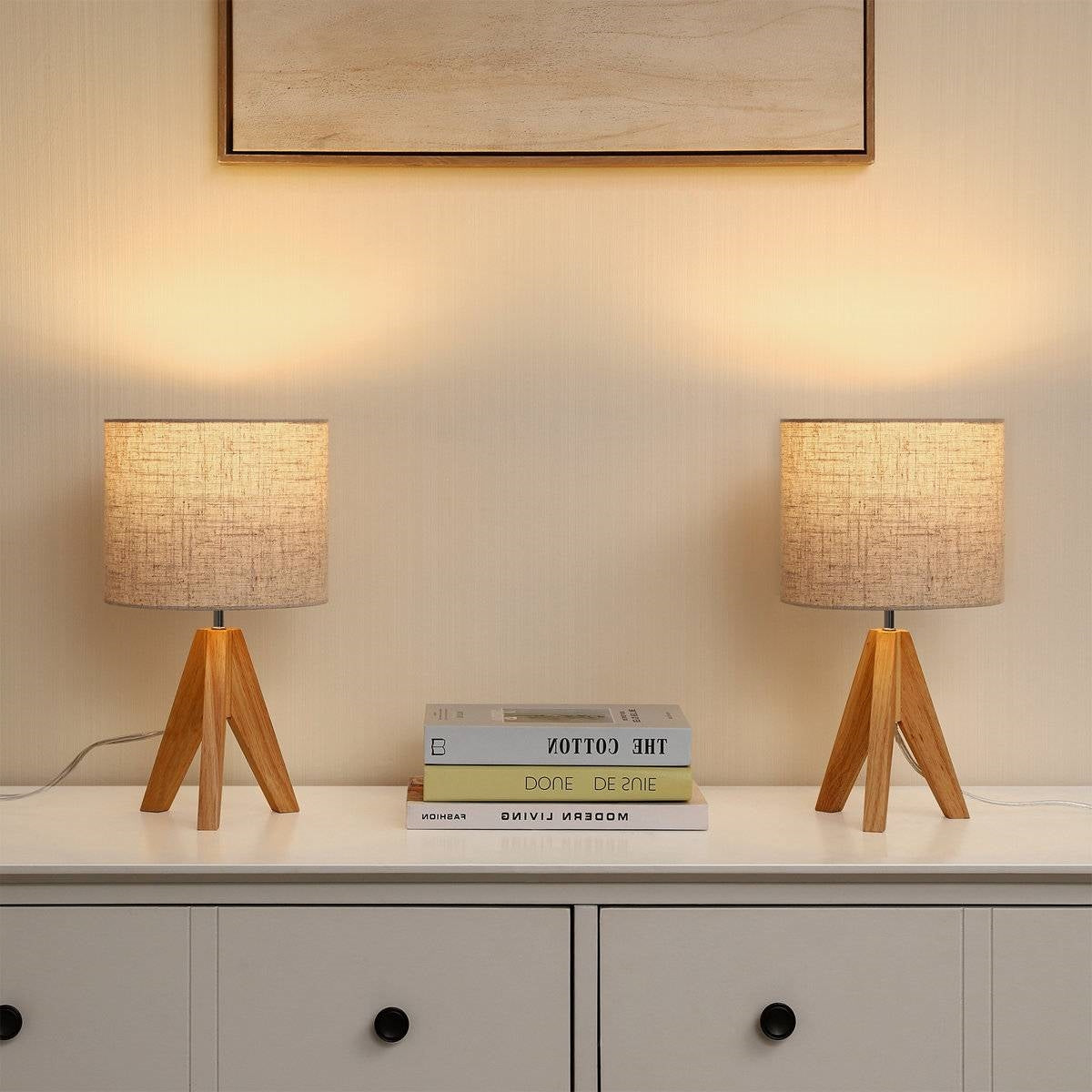 Set of 2 - Solid Wood Tripod Table Lamp with Beige Linen Drum Shade lighting up a room on a white cabinet.