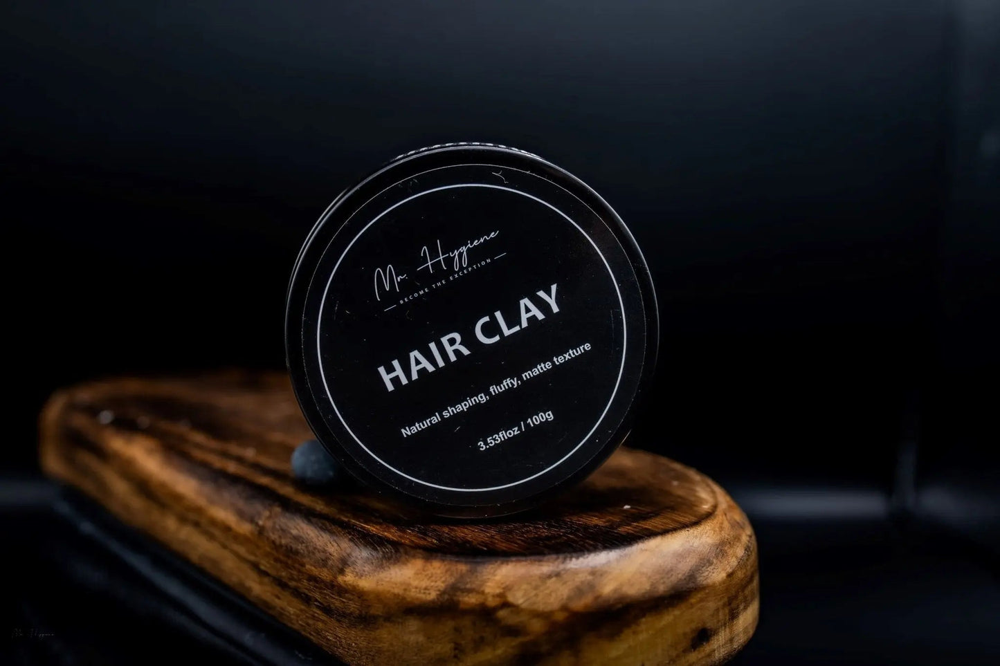 Matte Finish Hair Clay - Strong Hold. Zero Shine. All-Day Control. in black container on wooden surface