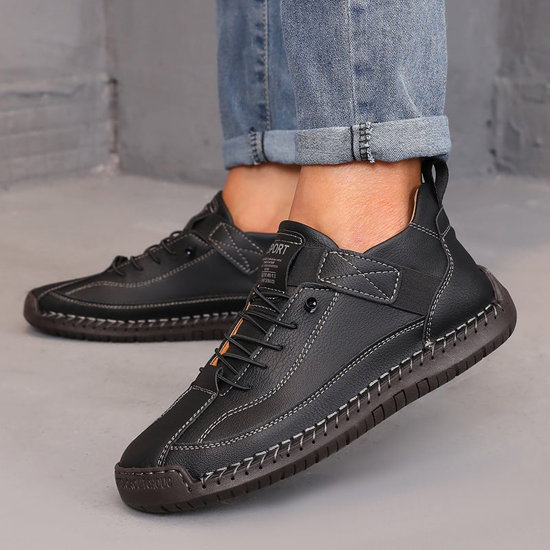 Stylish black leather sneakers paired with rolled-up jeans on a concrete background.