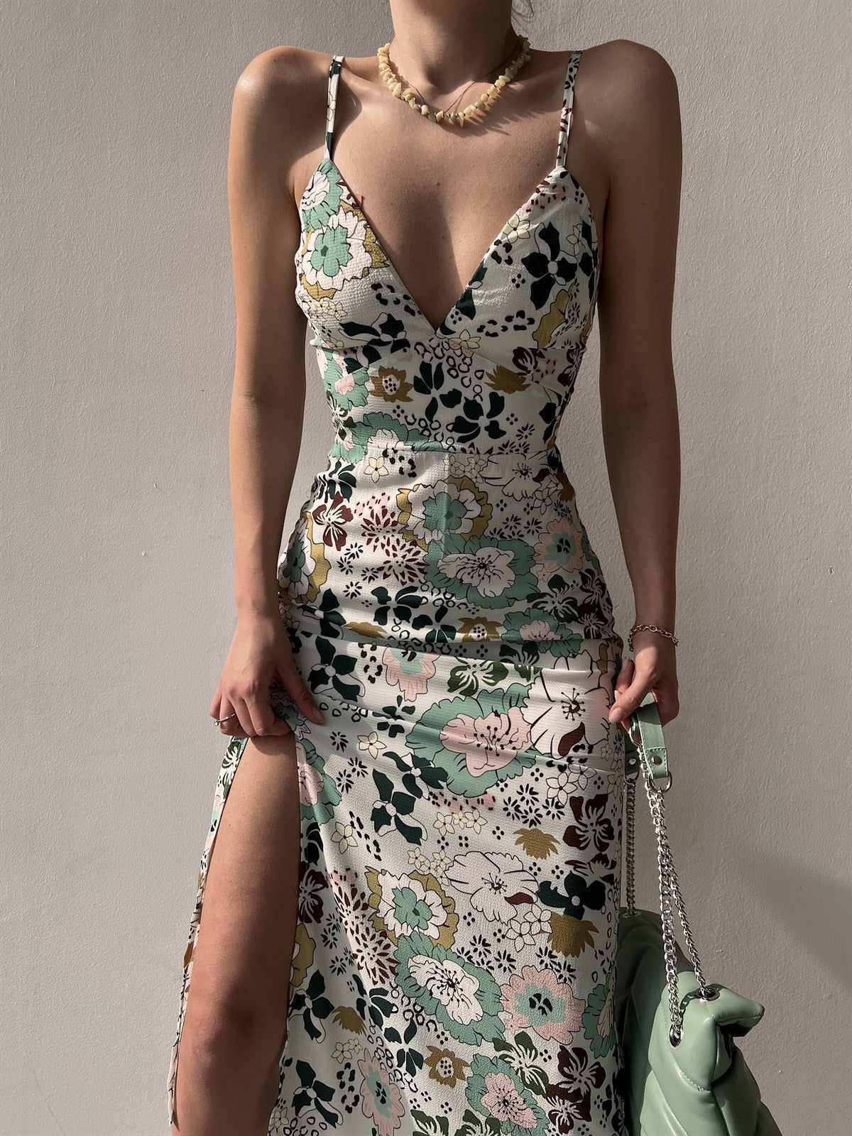 Woman wearing Women's Printed Backless Slit Sling Dress with floral pattern, spaghetti straps, low-cut back, and side slit.