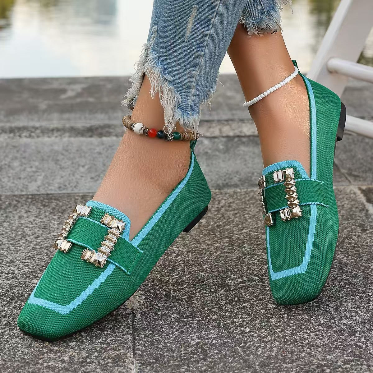 Stylish green loafers with decorative buckles paired with distressed jeans and ankle bracelets.