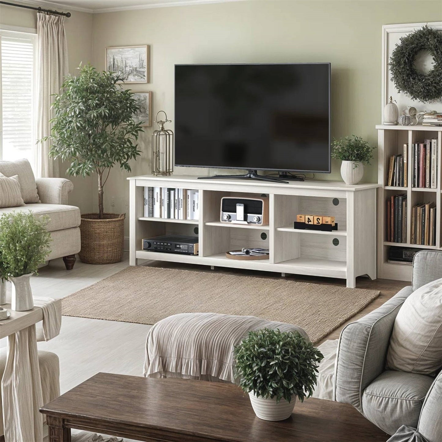 Farmhouse TV Stand in White Wood Grain Finish - for TVs up to 70-inch in a cozy living room setting with decor and greenery.