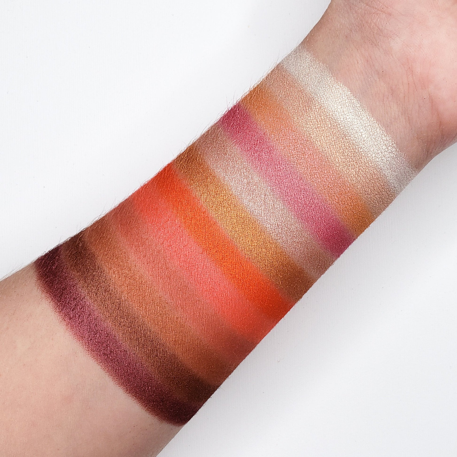 Swatches of the GOLDEN PEACH EYESHADOW PALETTE CP15 showcasing varied shimmer and matte shades on arm