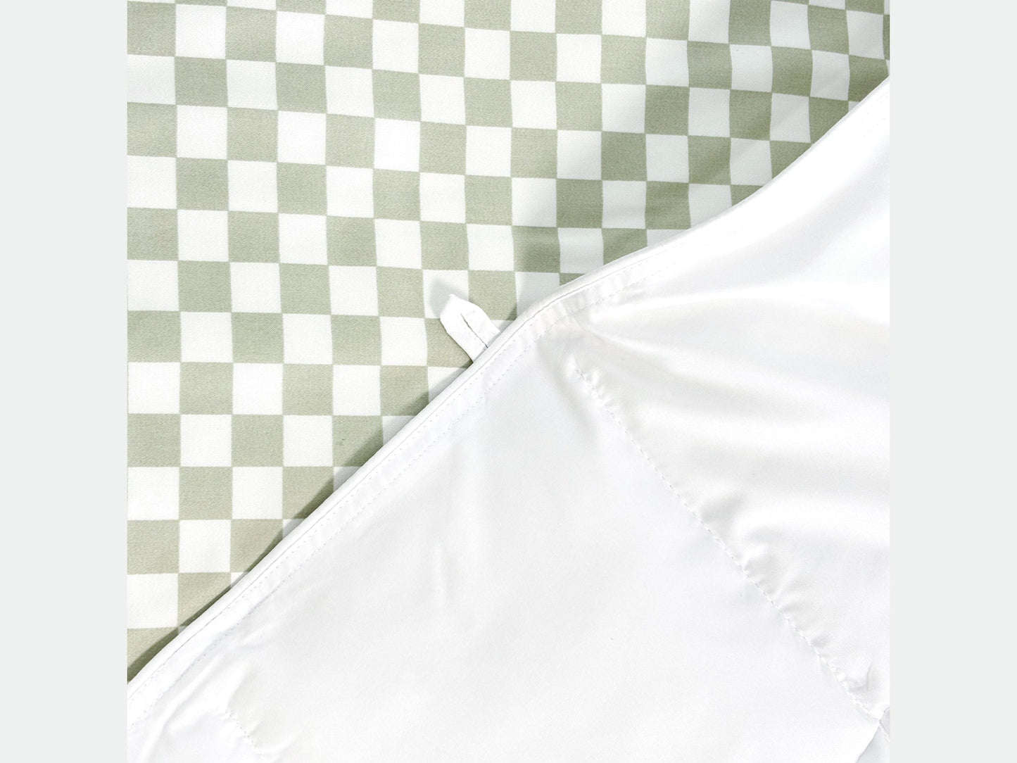 Green checkered SHNUGGLE SNAP-EZ Quilt with white snap-on feature for easy attachment to bedding.