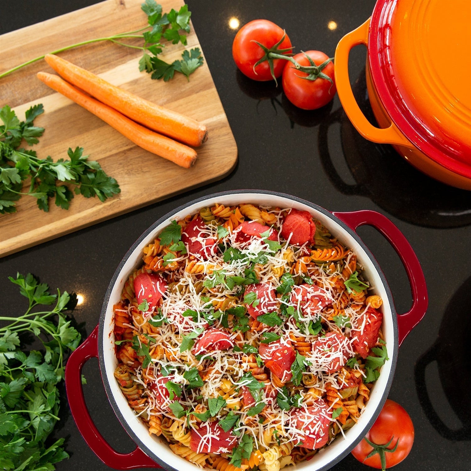6 Quart Large Red Enamel Cast-Iron Dutch Oven Kitchen Cookware filled with colorful pasta dish, vegetables on a cutting board nearby