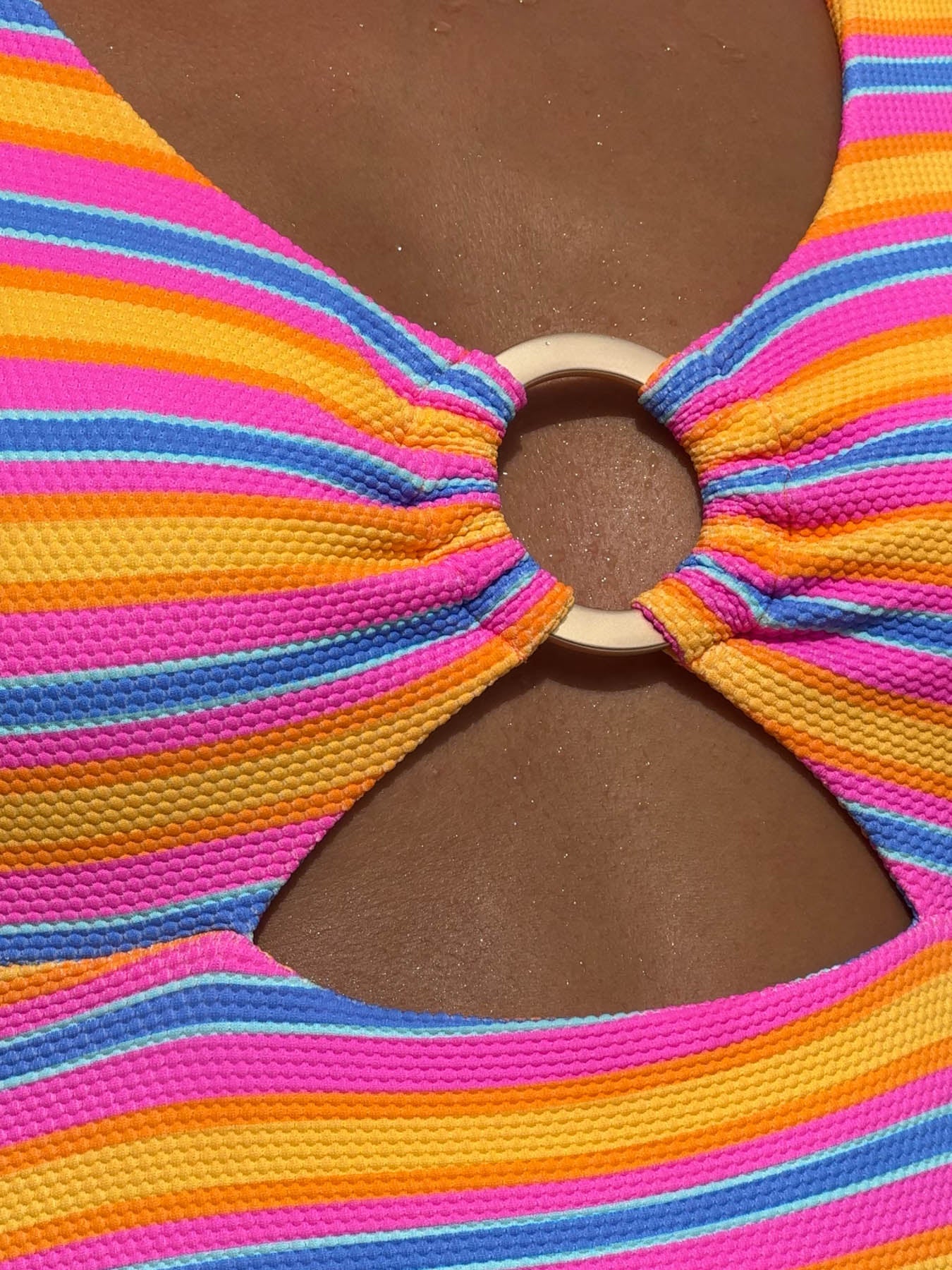 Close-up of randi one piece - sahara swimsuit with colorful stripes and center ring detail.