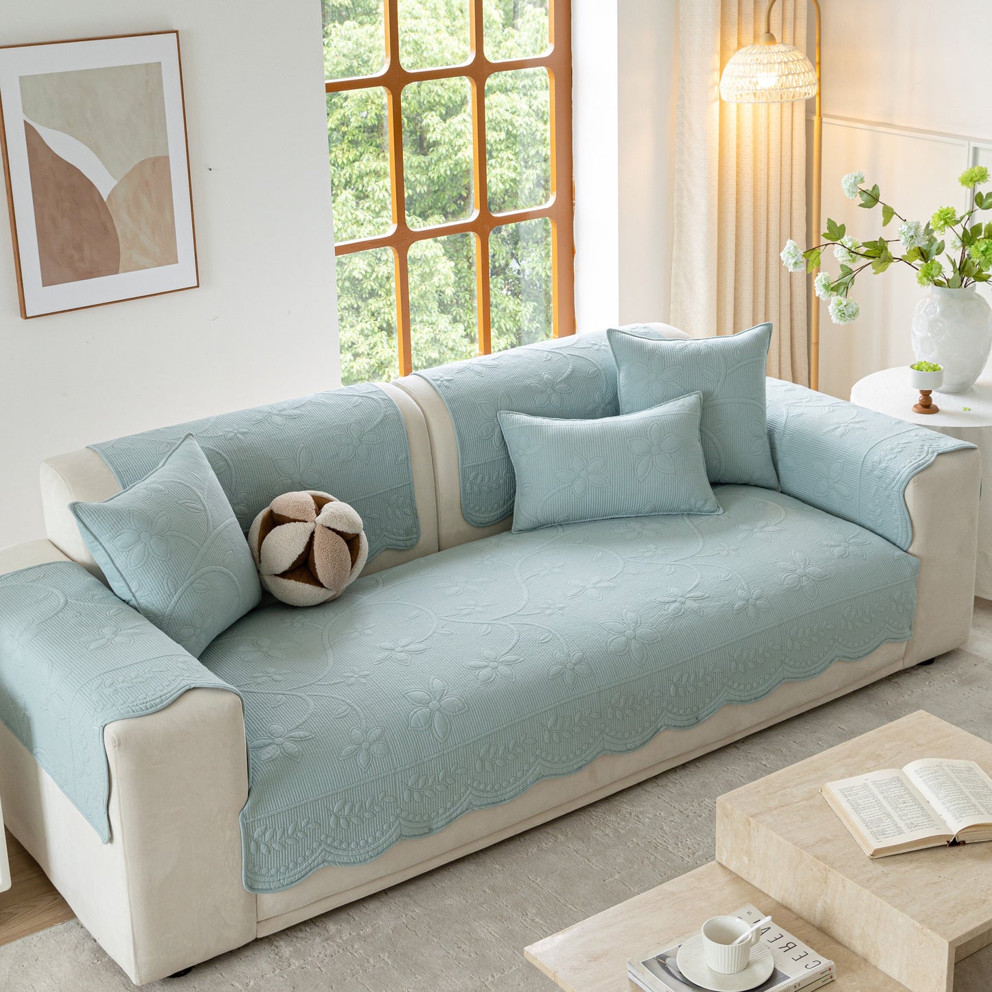 Floral Cotton Quilted Sofa Cover, Non-Slip Couch Protector with Scalloped Edges on a beige sofa in a bright living room.