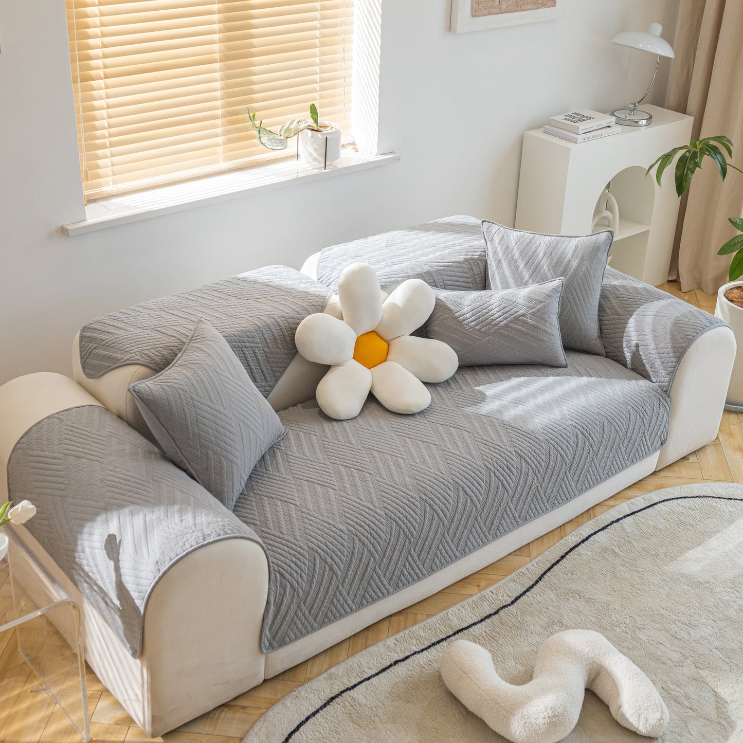 Living room with gray Quilted Geometric Cotton Sofa Cover, Non-Slip & Thick Padded Furniture Covers on cream sofa with decorative pillows.