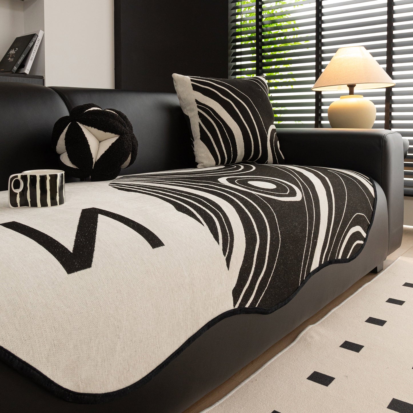 Abstract Art Sofa Cover with Wave Edge, Non Slip Couch Cover for Stylish Homes on a black leather sofa in a modern living room.