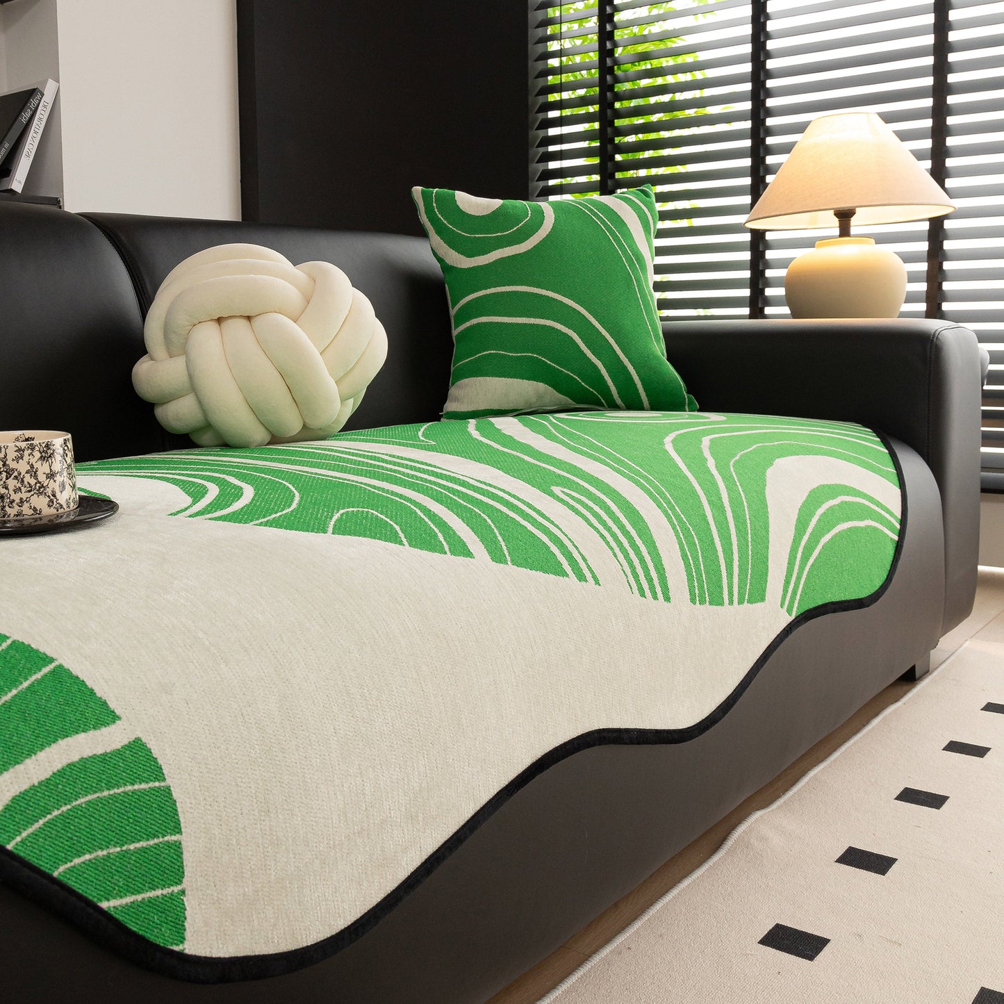 Green abstract art sofa cover with wave edge, non slip couch cover for stylish homes, on a black sofa, enhancing modern living décor.