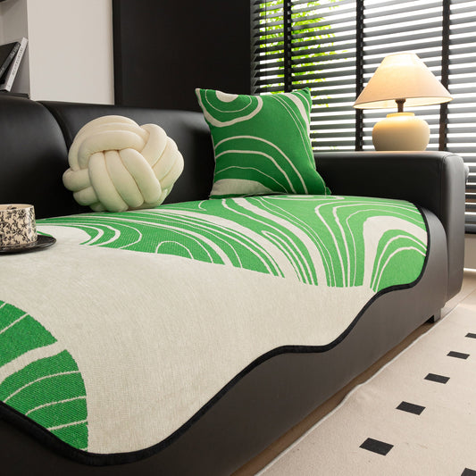 Green abstract art sofa cover with wave edge, non slip couch cover for stylish homes, on a black sofa, enhancing modern living décor.