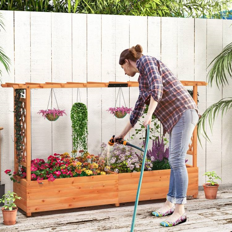 Woman watering plants in a Solid Fir Wood Rectangle Raised Garden Bed with Side Trellis filled with colorful flowers and herbs.