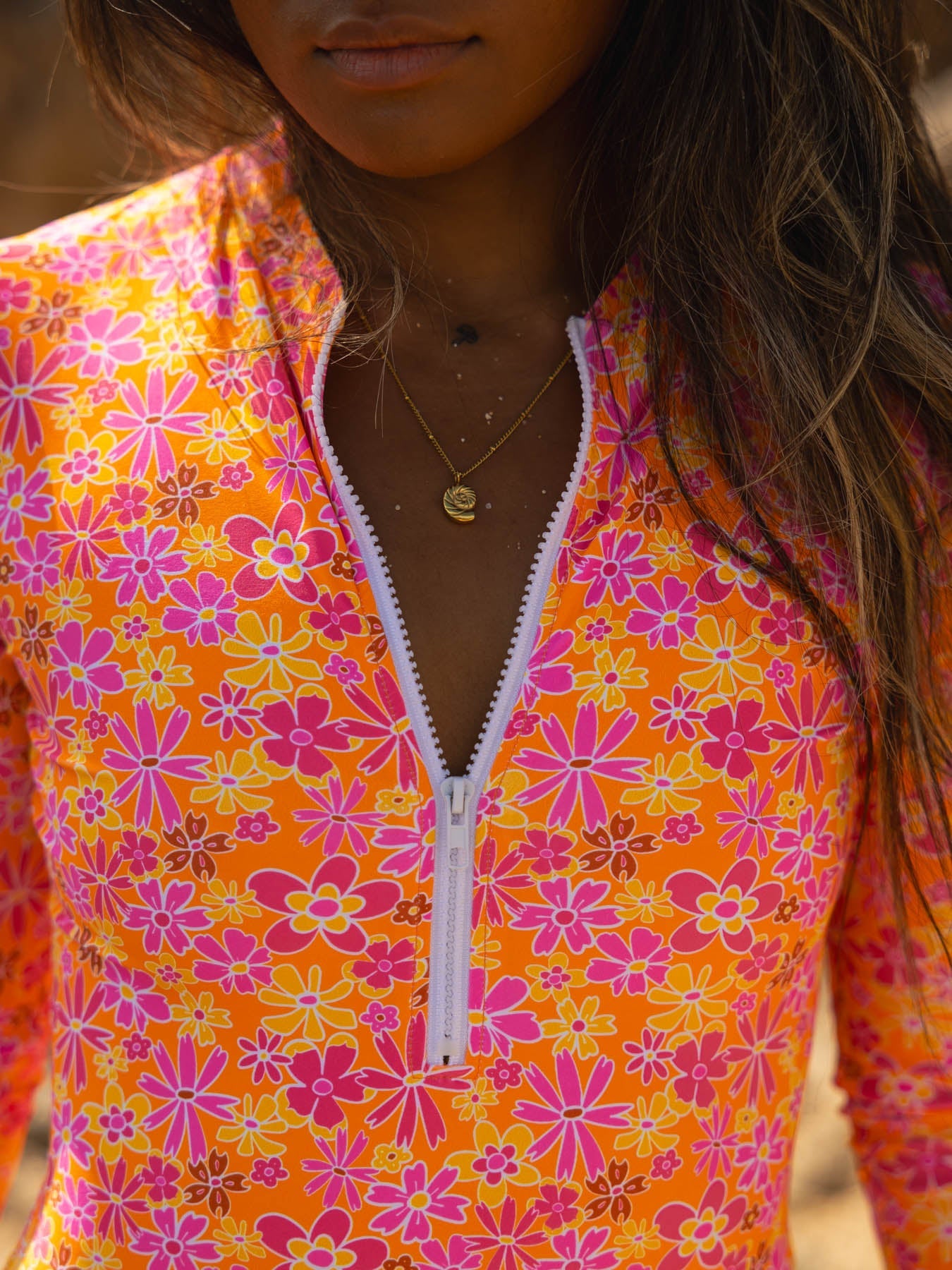 Woman wearing audrey one piece - marrakesh surf-style swimsuit with vibrant floral design and front zipper, providing sun protection.