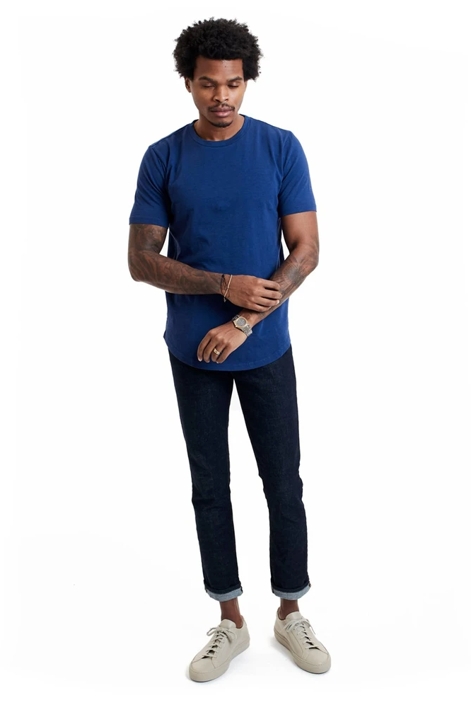 Man wearing a blue 100% Pima Cotton Short Sleeve T-shirt with casual jeans against a white background.