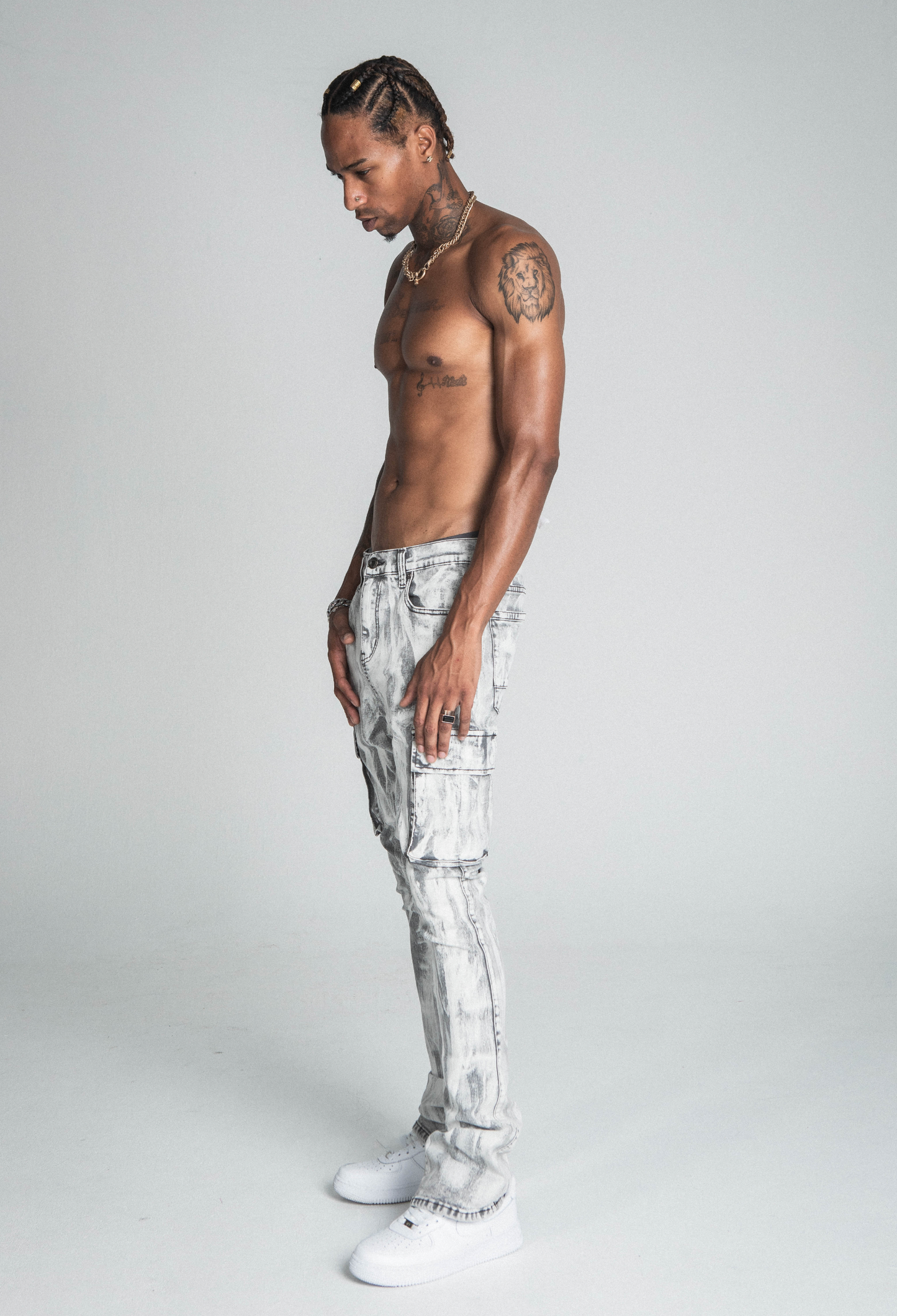 Model wearing AJ29SK GREY/WHITE WASH STACKED CARGO JEANS with splash paint design, showcasing side view and detail of jeans.