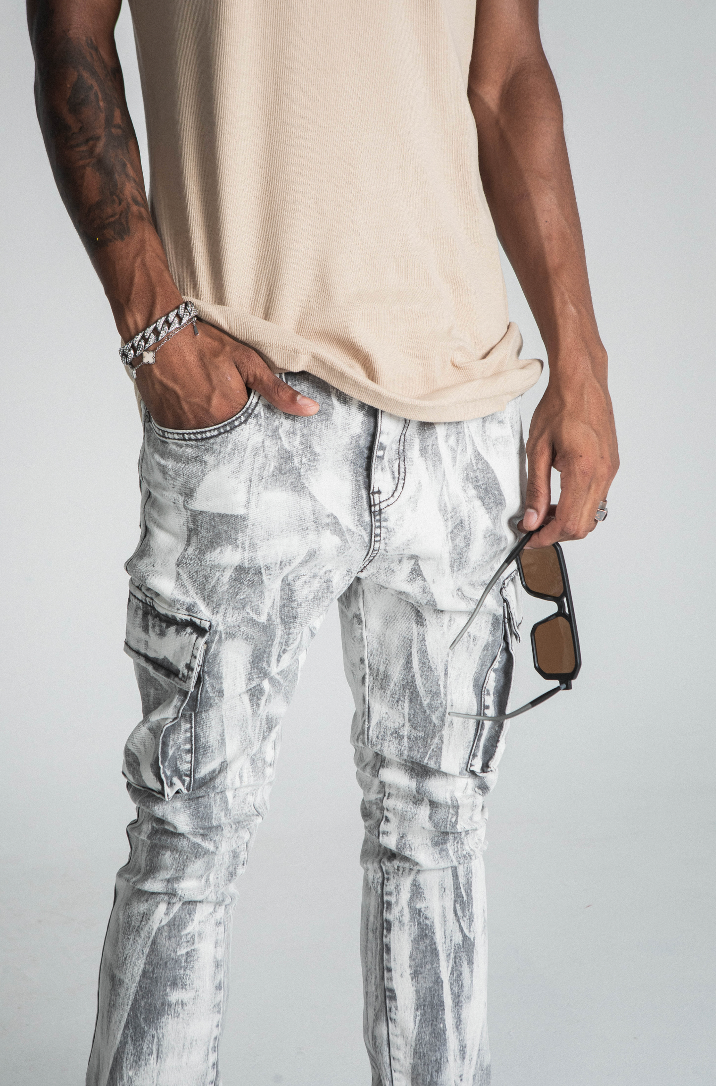 Model wearing AJ29SK GREY/WHITE WASH STACKED CARGO JEANS with paint splash design, cargo pockets, and mid-rise waist.