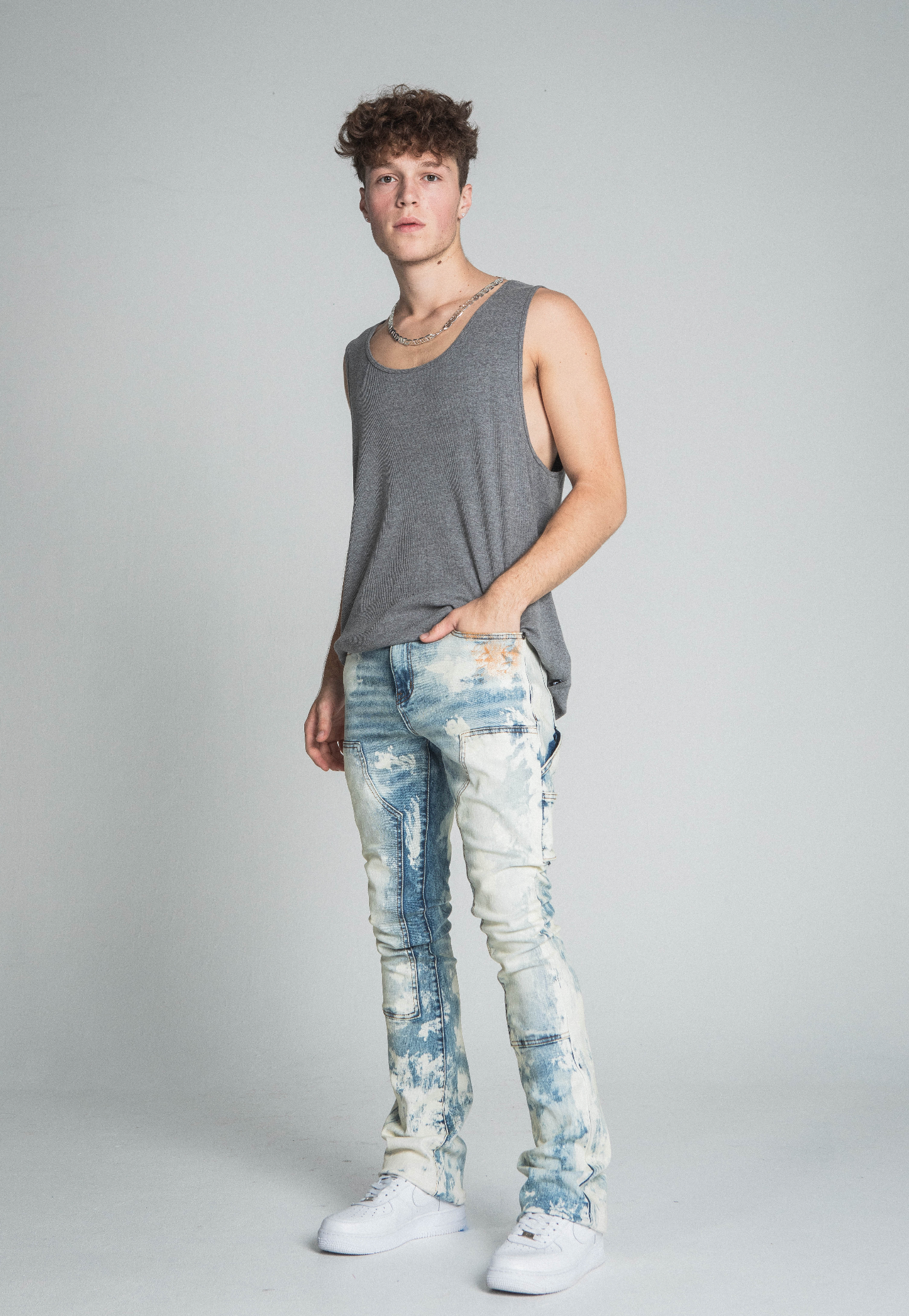 Model wearing AJ19SK OIL PAINT STACKED JEANS with cargo pocket and belt loops, featuring trendy oil pants design and zipper fly.
