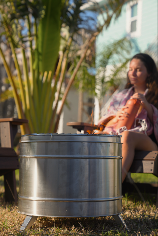Large Smokeless Fire Pit in garden setting with person relaxing in background