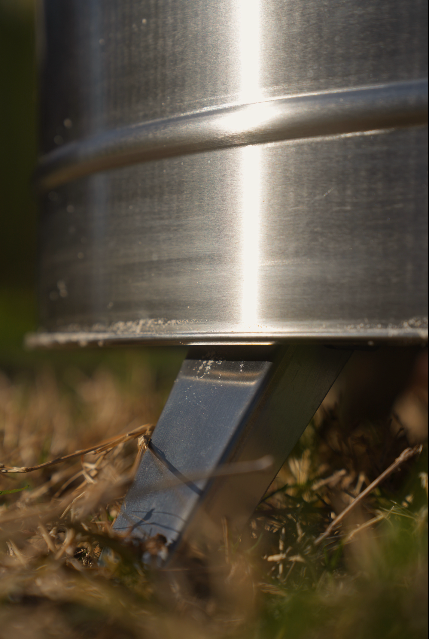 Close-up view of a metal leg of a Large Smokeless Fire Pit on grass, highlighting its sturdy design.