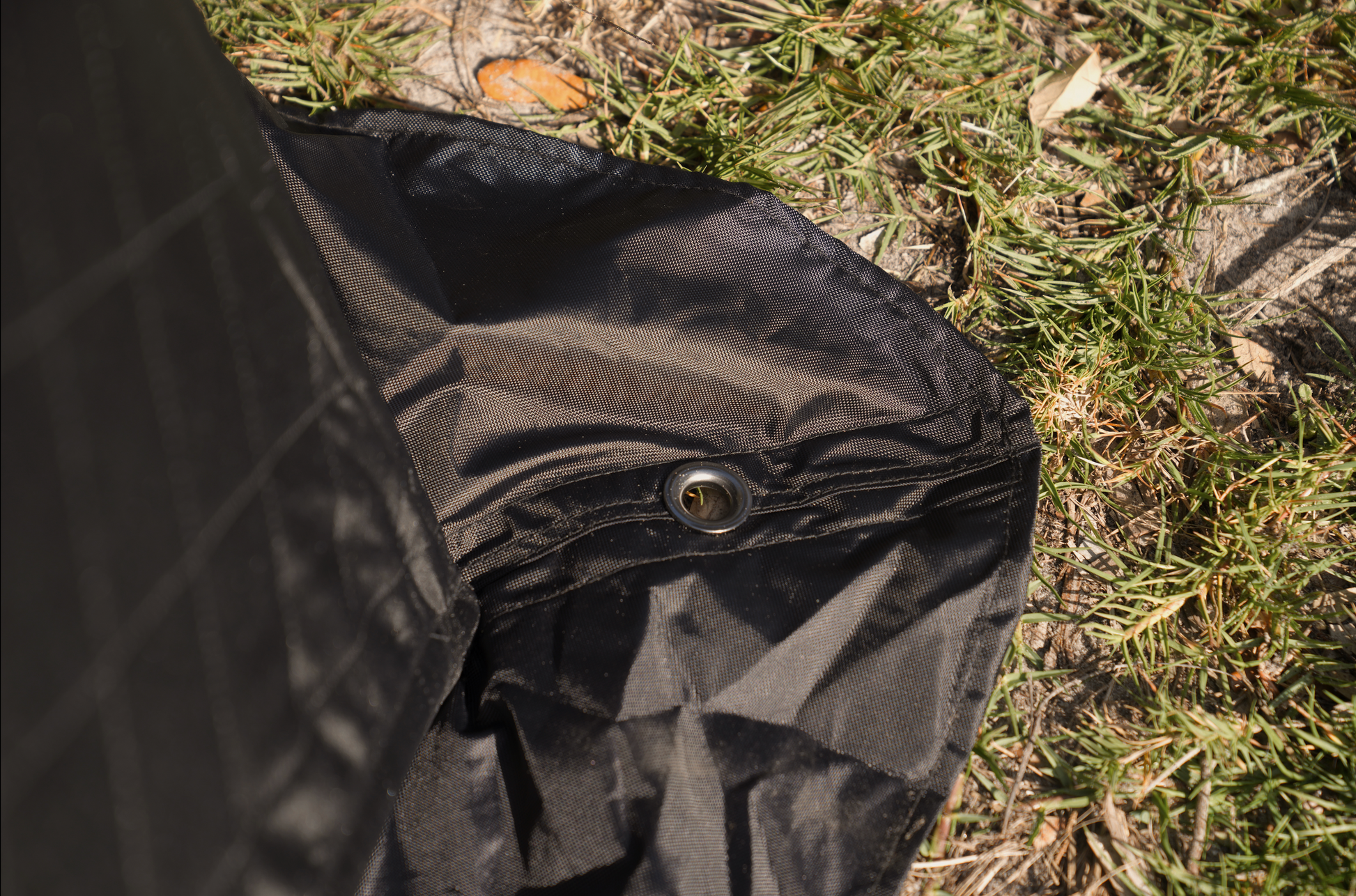 Close-up of Mini Cube Sauna Tent (2-person; tent only) fabric and grommet detail on grass.