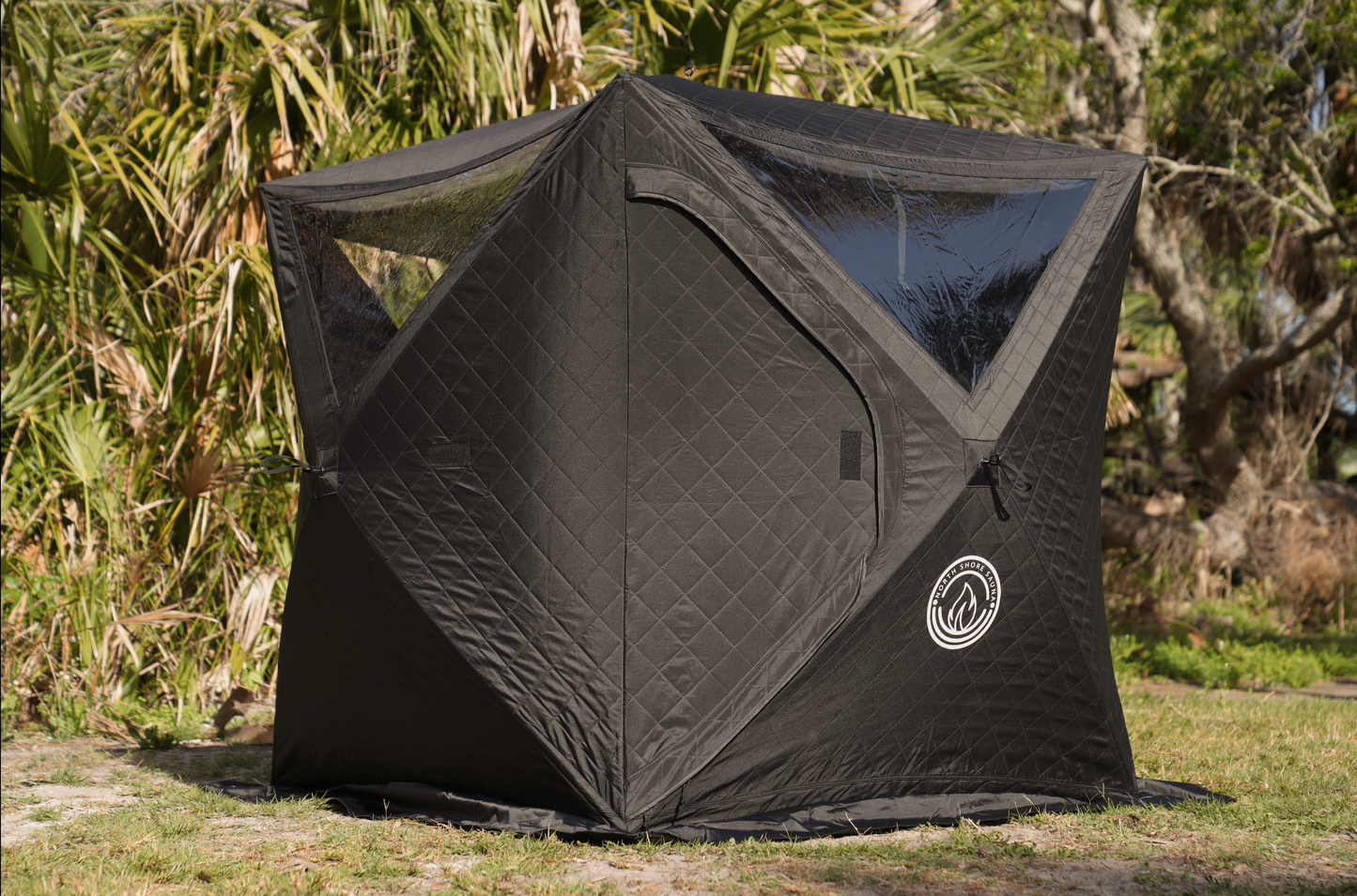 Black Mini Cube Sauna Tent (2-person; tent only) set up outdoors in a grassy area with surrounding greenery.