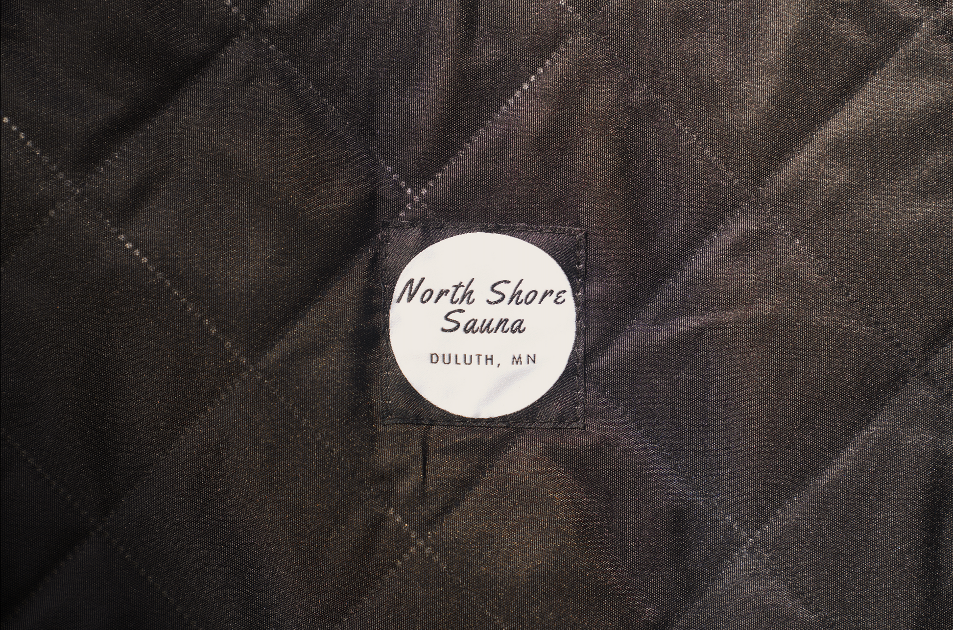 Quilted fabric with embroidered North Shore Sauna logo, Duluth, MN.