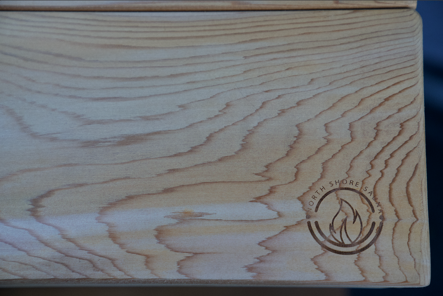 Close-up of portable sauna bench surface with wood grain and logo