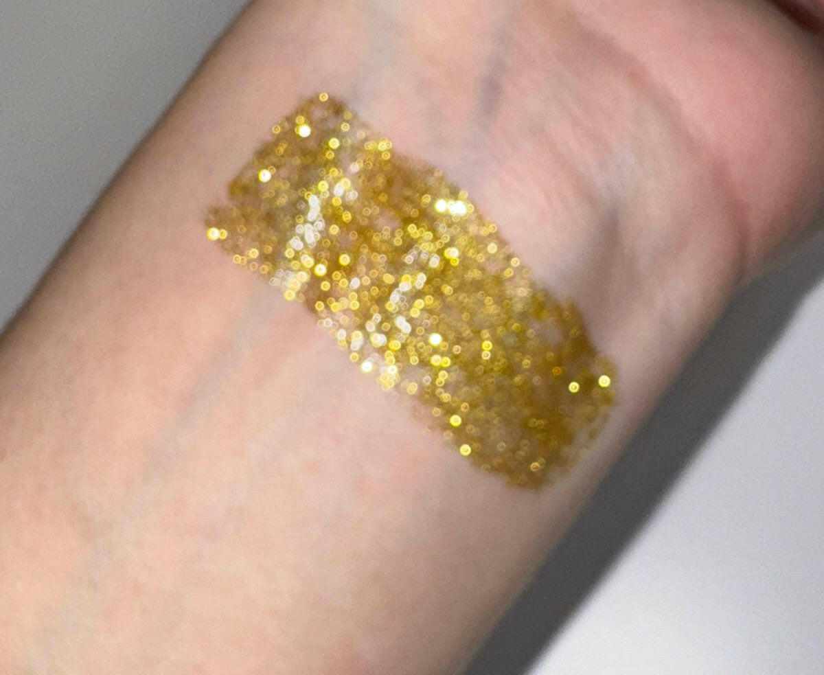 Swatch of Spellbound - Flicker Glitter Eyeliner in yellow gold on skin.