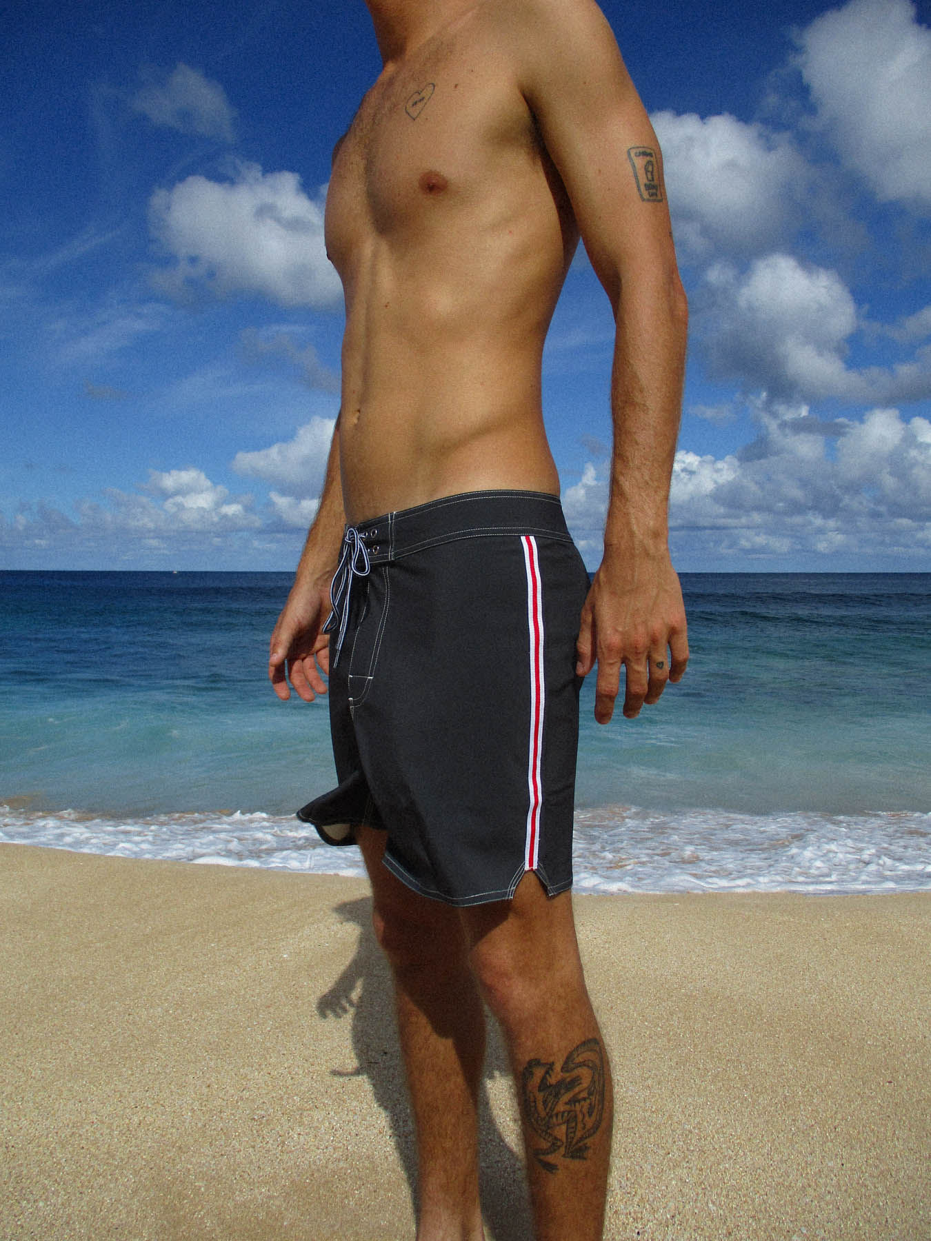 Man wearing pirate black the classic boardshort - yards with textured 4-way stretch fabric at the beach.