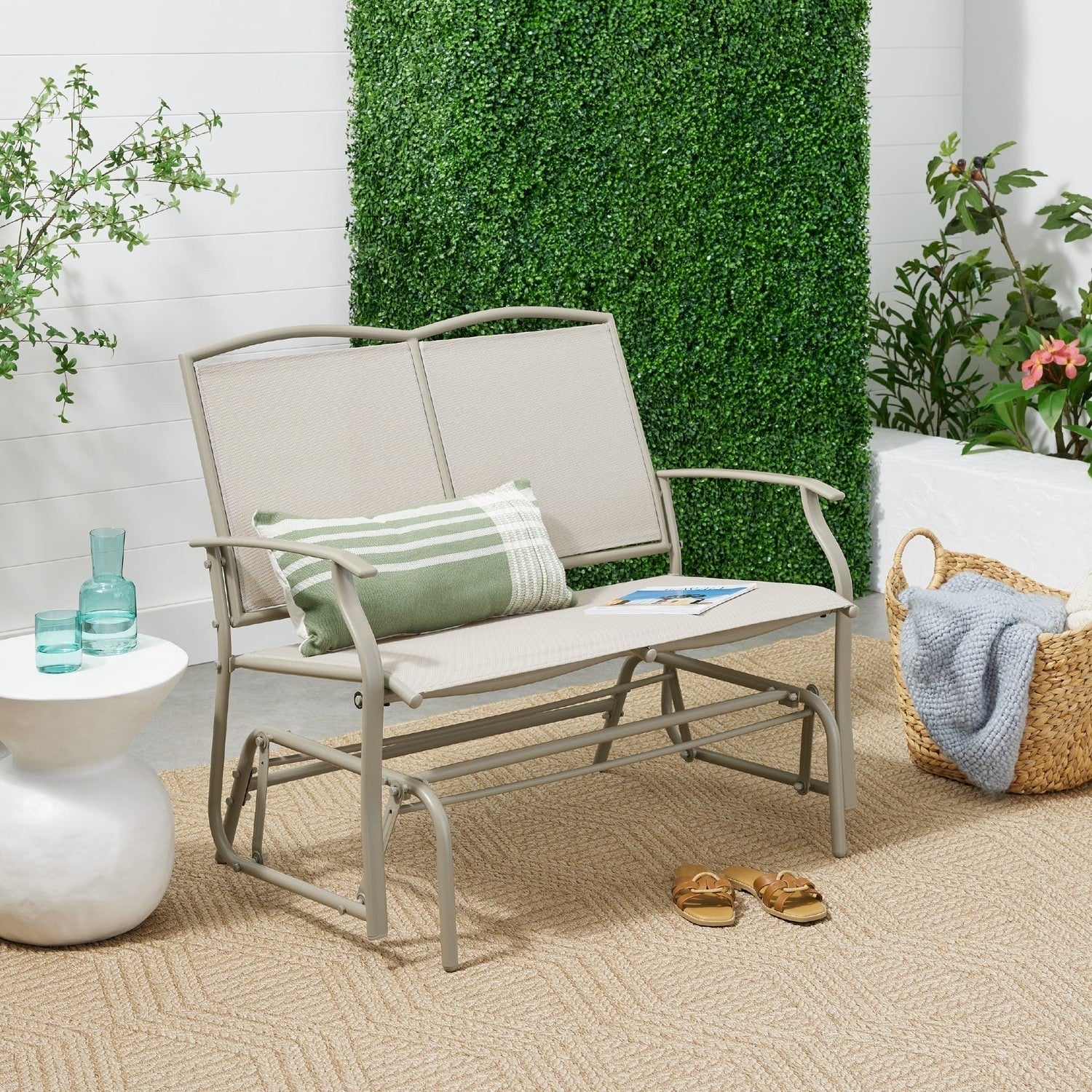2 Seat Mesh Patio Loveseat Swing Glider Rocker with Armrests in Taupe on a patio with plants and decor