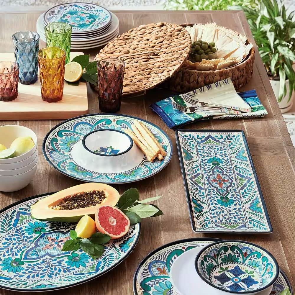 12-Piece Melamine Dinnerware Plates Bowls Set with Blue Floral Pattern on a table with assorted dishes and glasses