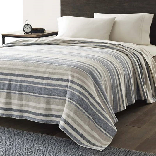 Twin size Navy Blue Tan Cream Chevron Stripe Lightweight Cotton Blanket draped on a bed.