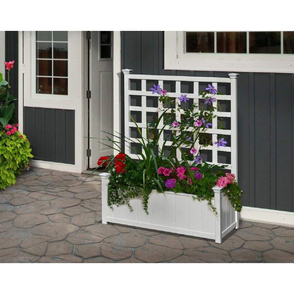 Outdoor White Vinyl Garden Planter Box with Trellis filled with colorful flowers against a house wall on a stone patio.